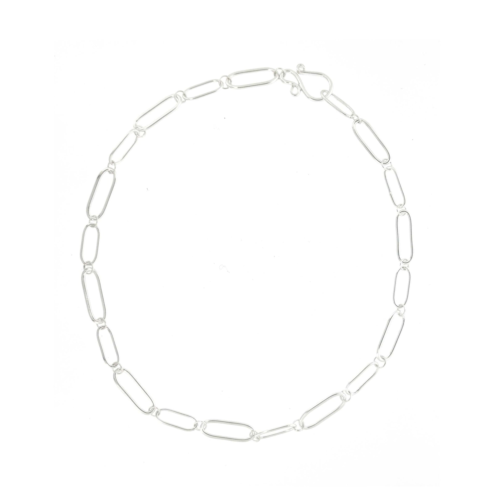 A silver chain necklace with open oblong links of different sizes and an s-clasp.