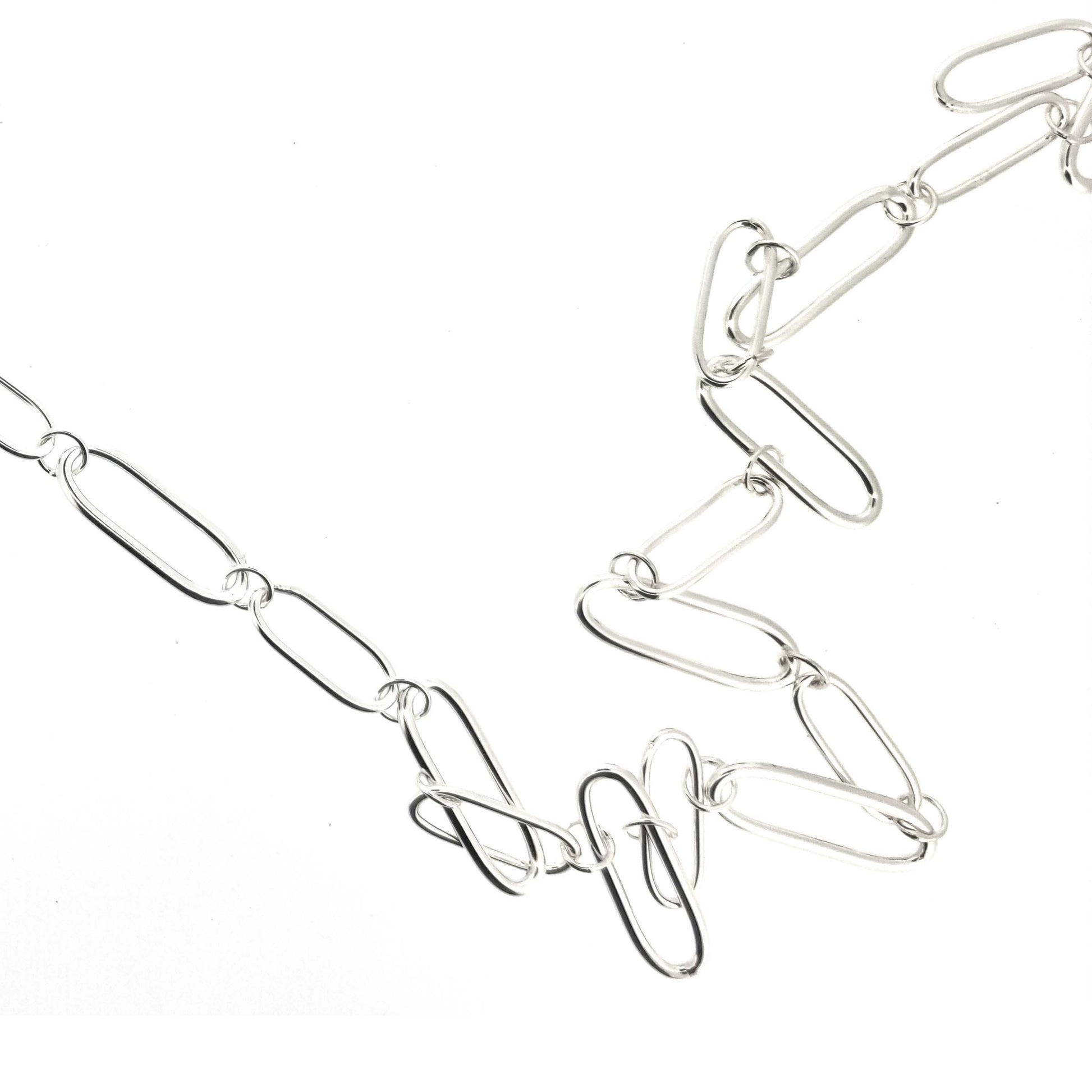 A silver chain necklace with open oblong links of different sizes.