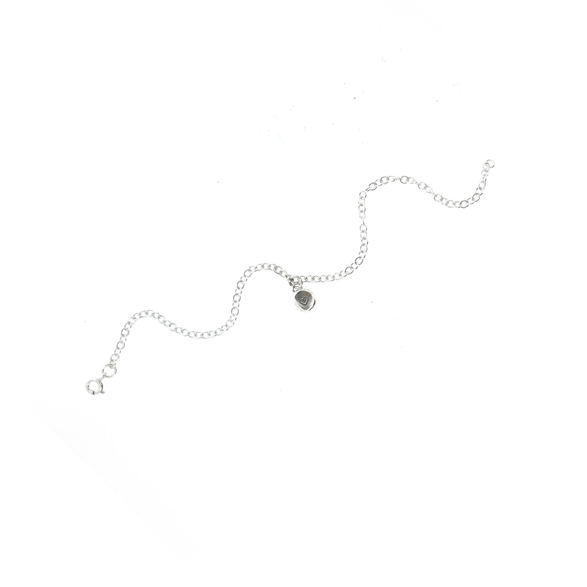 A silver chain bracelet with an organic style round charm engraved with a small heart.