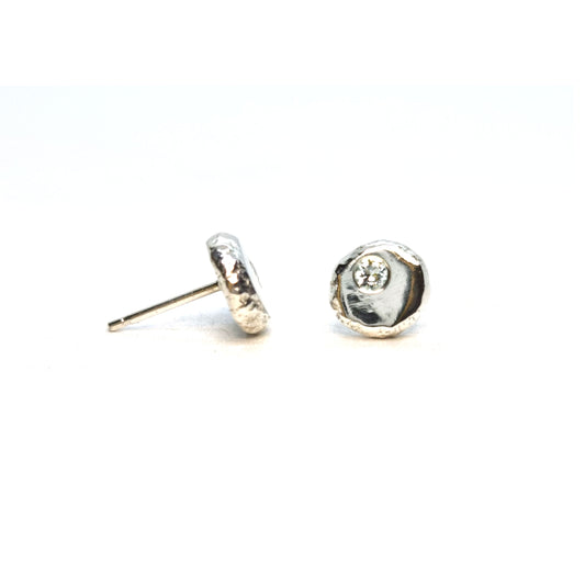 Silver flat round 'pebble' stud earrings with a round CZ set off centre.
