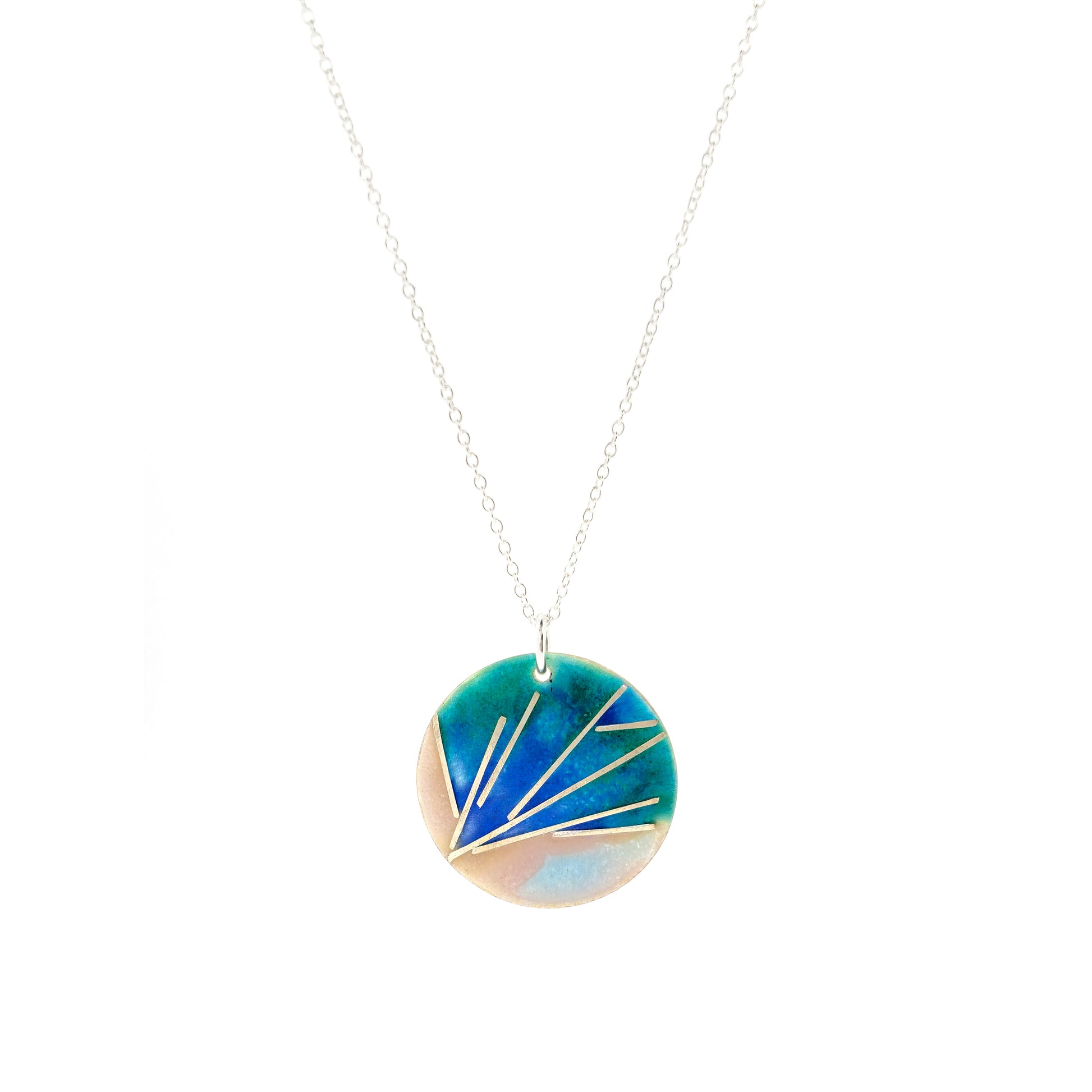A round silver pendant with a spray of silver lines and blue, pink, and green enamel. On a silver chain.