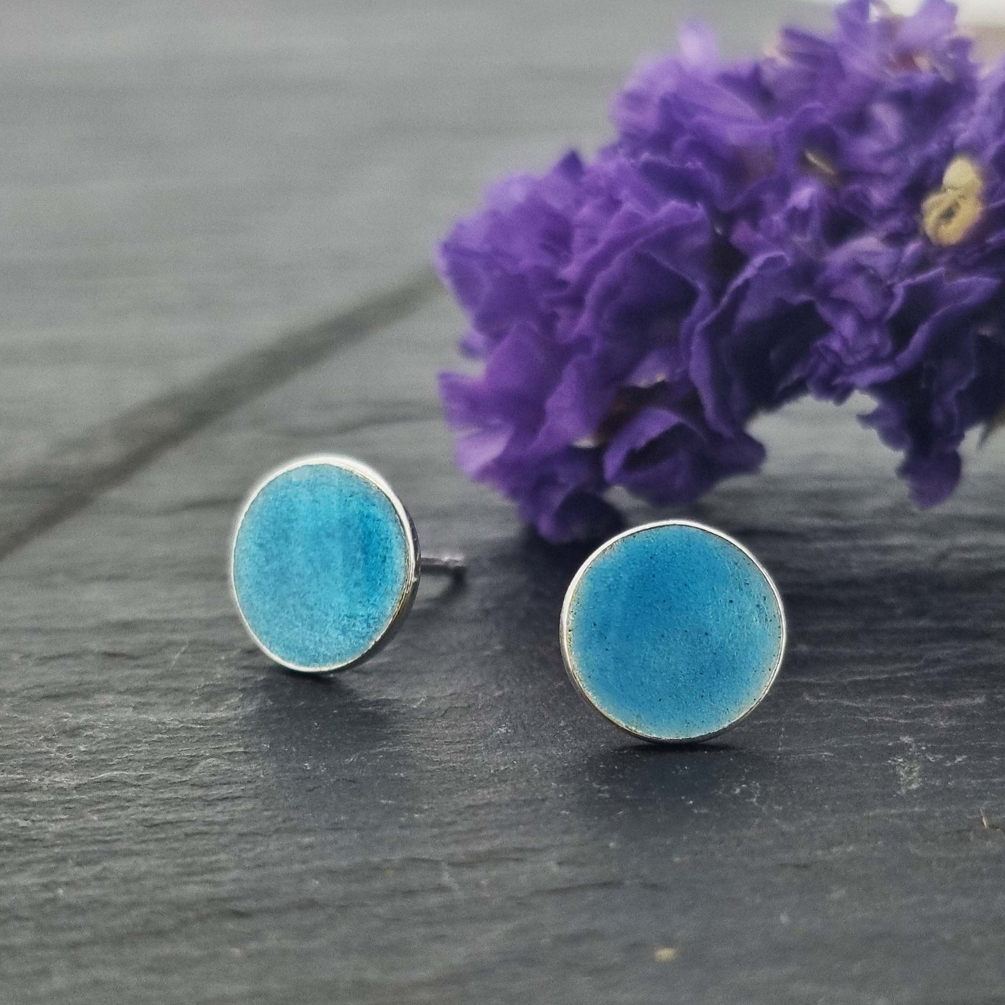 Round silver stud earrings with turquoise blue enamel. 12mm. Pictured with flowers.