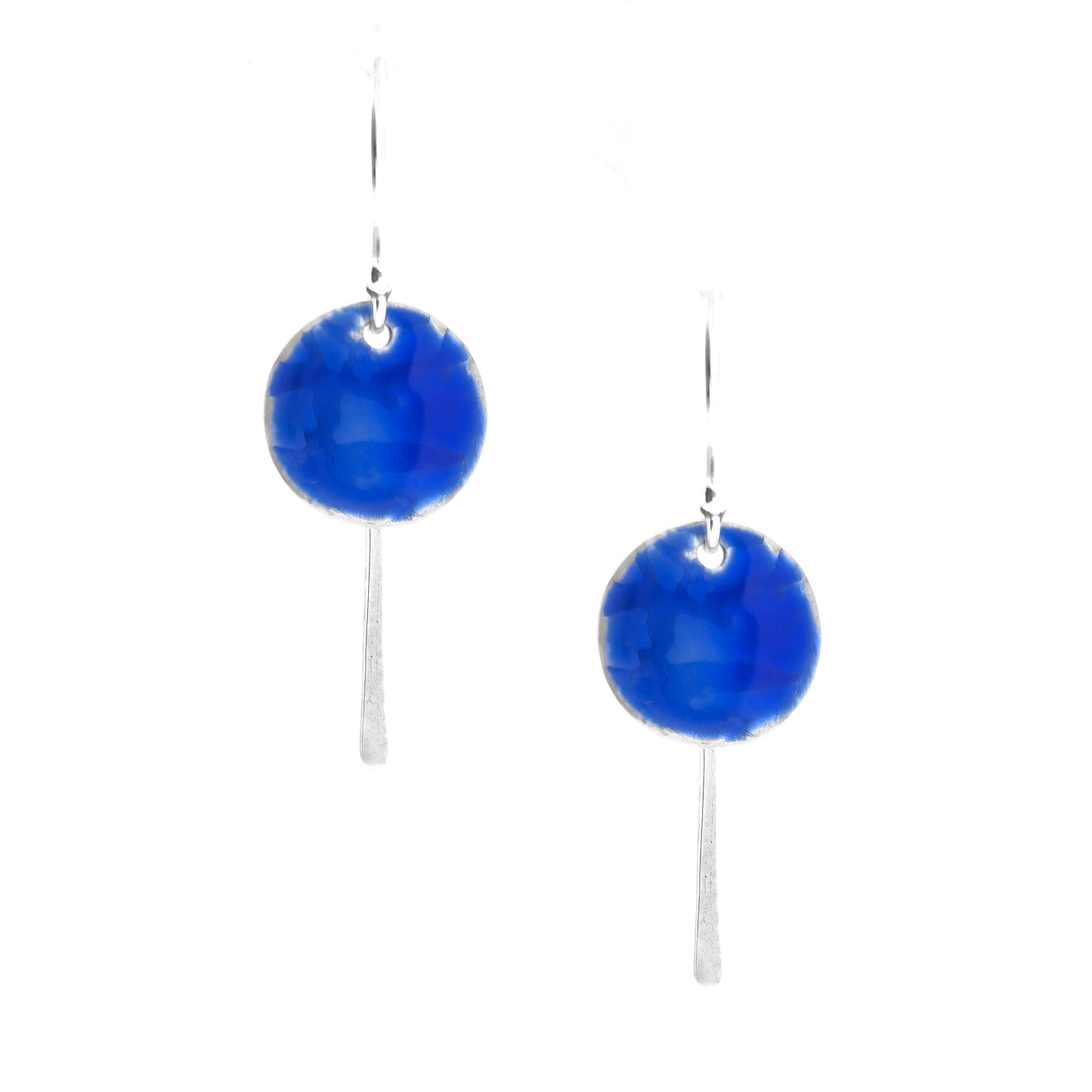 Silver drop earrings featuring a rustic round disc with a lined pattern covered with dark blue enamel. slim silver tag hangs behind and below. On silver ear hooks.