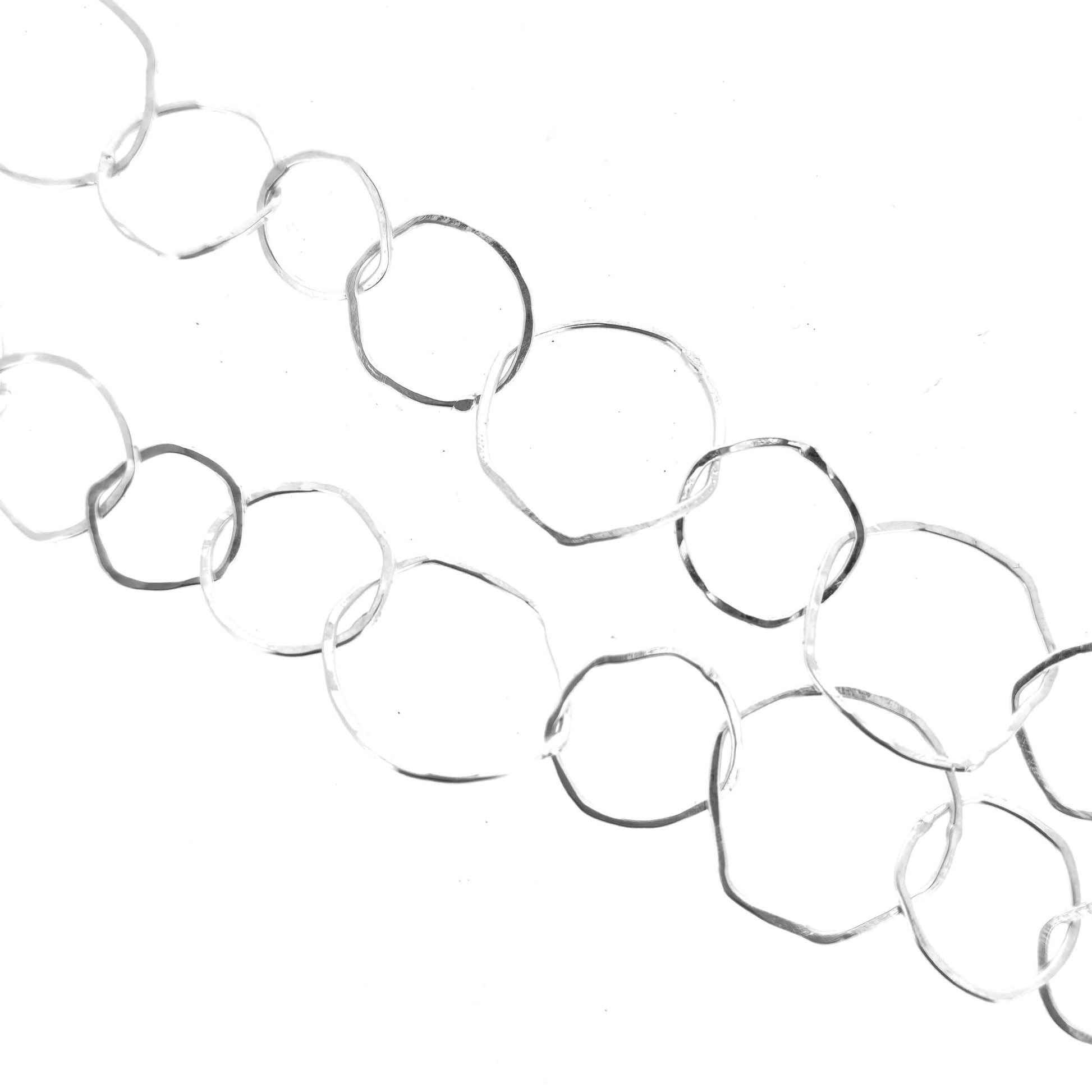 Part of a silver necklace with rustic interlocking circular links on a white back ground