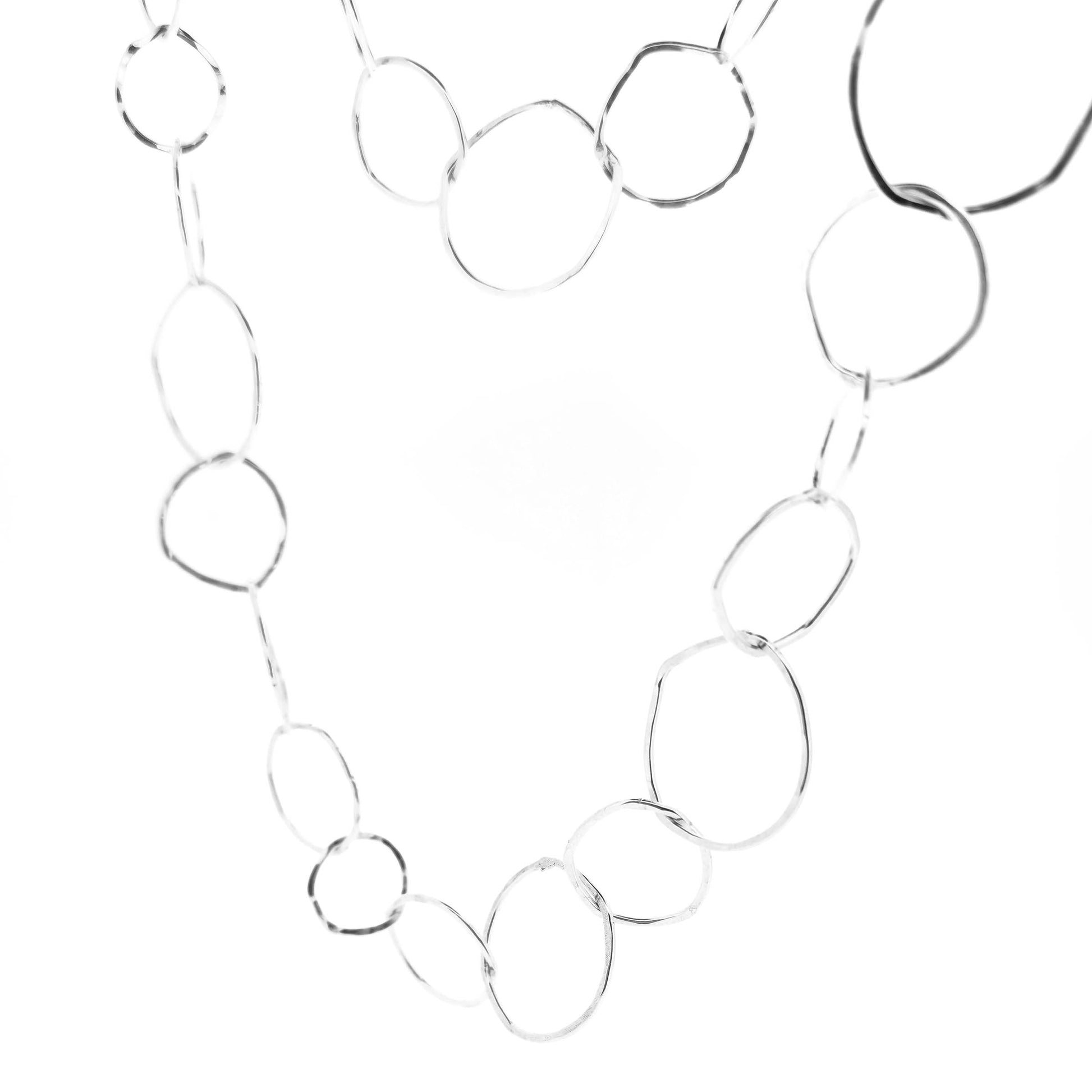 Silver necklace with rustic interlocking circular links on a white back ground