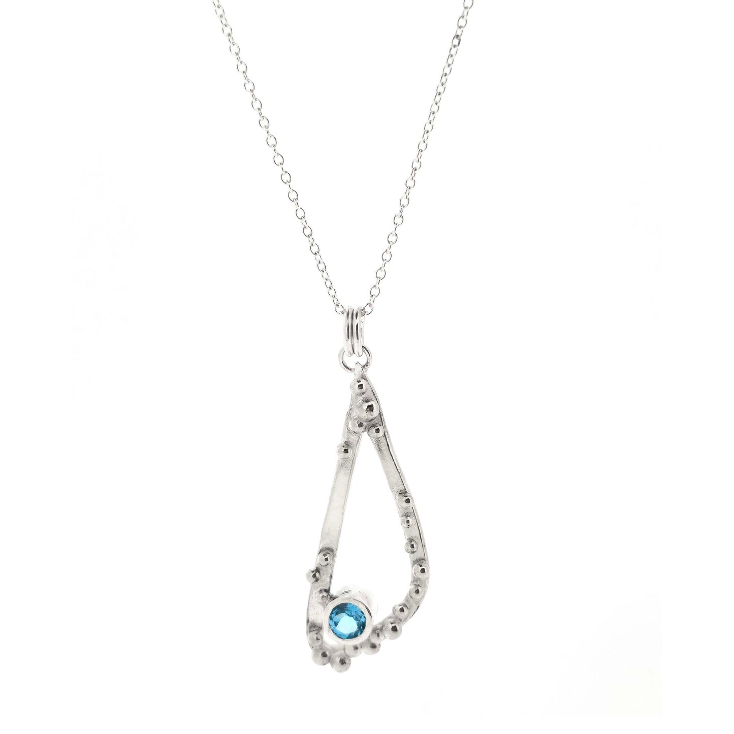 Silver asymmetrical soft open triangle pendant with silver balls and a blue topaz gemstone on a silver chain. Shown on a white bcakground.