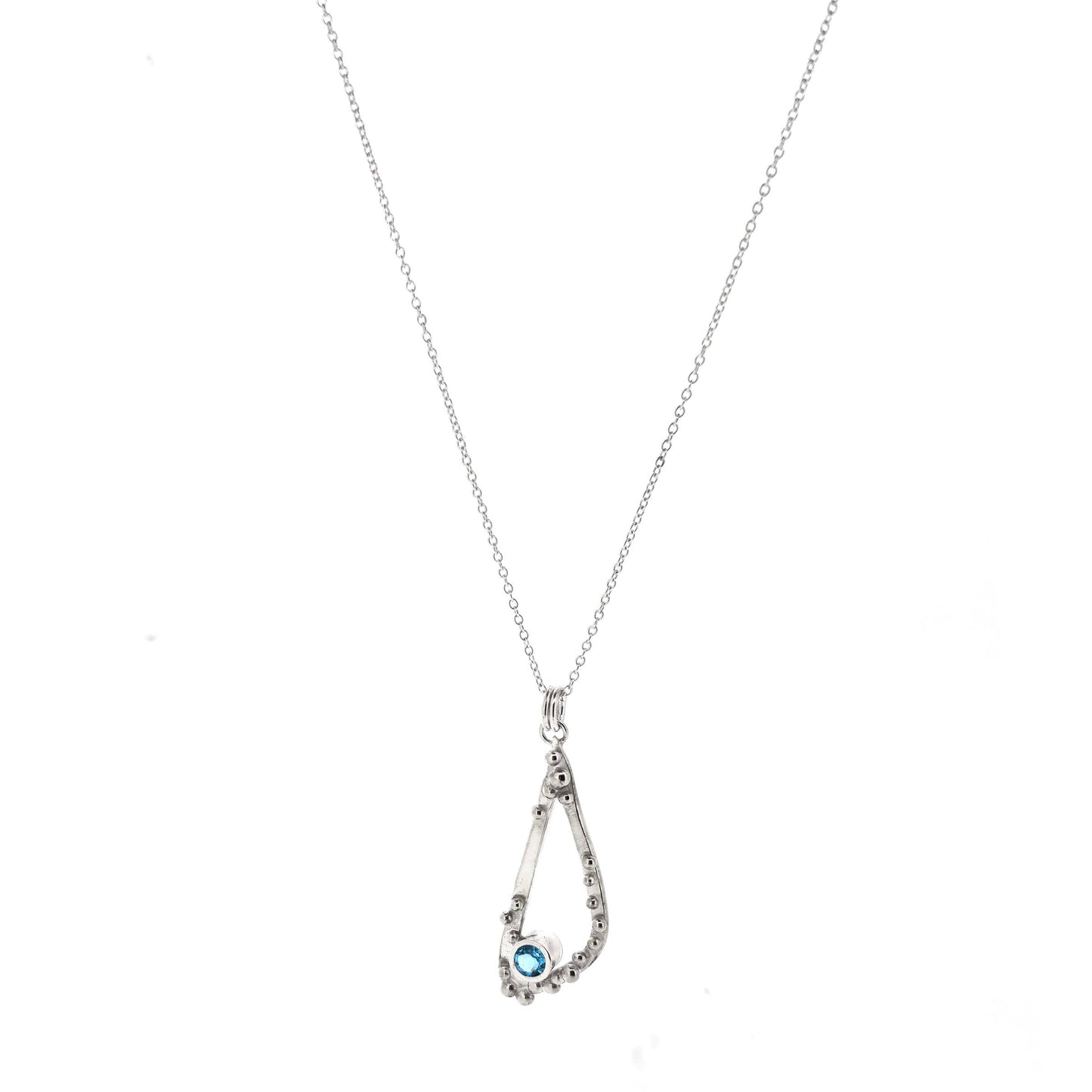 Silver asymmetrical soft open triangle pendant with silver balls and a blue topaz gemstone on a silver chain. Shown on a white background.