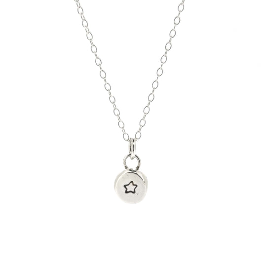 A silver flat pebble pendant with a black 5 pointed star on it. On a silver chain.