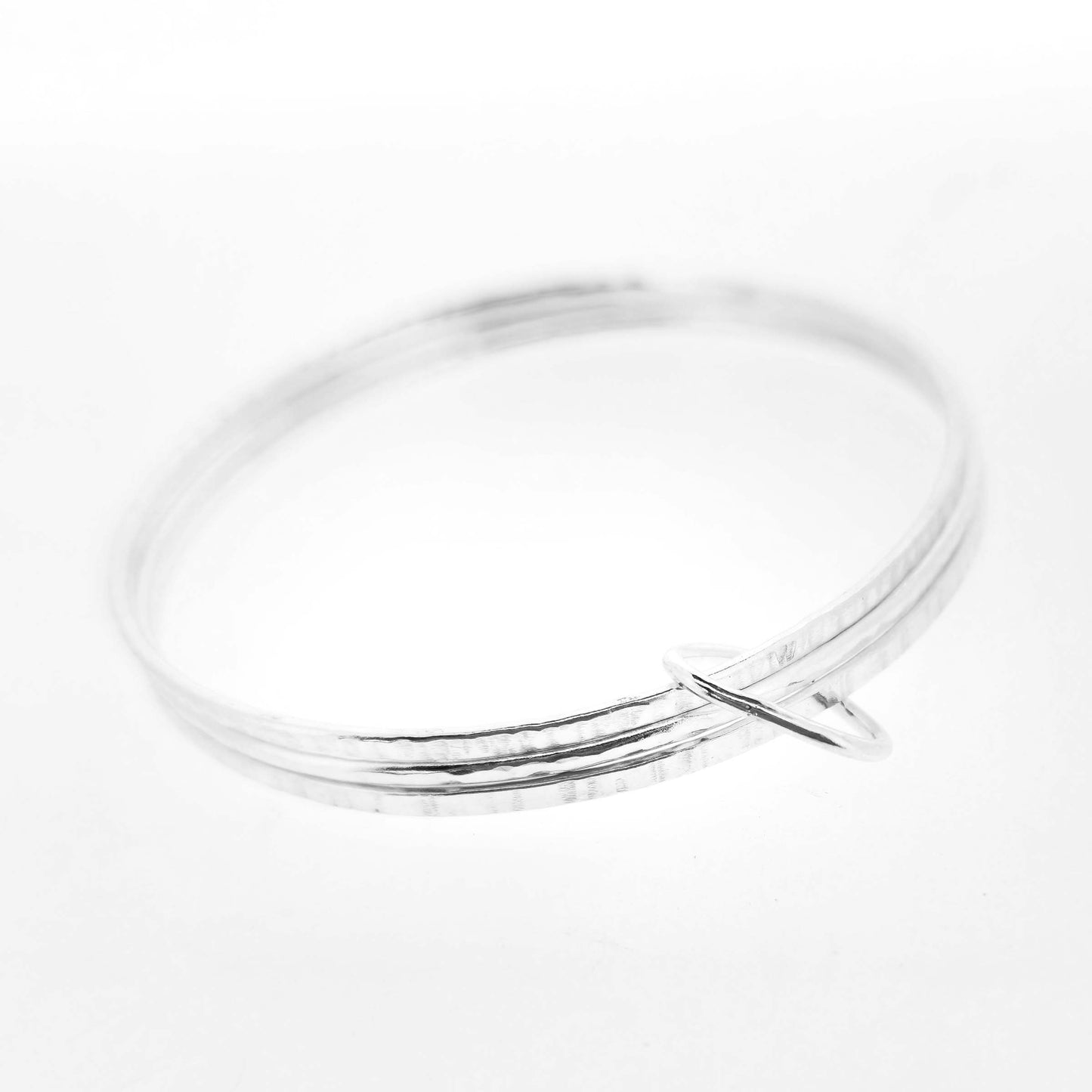 Triple textured silver bangle connected with soft edged open triangle charm.