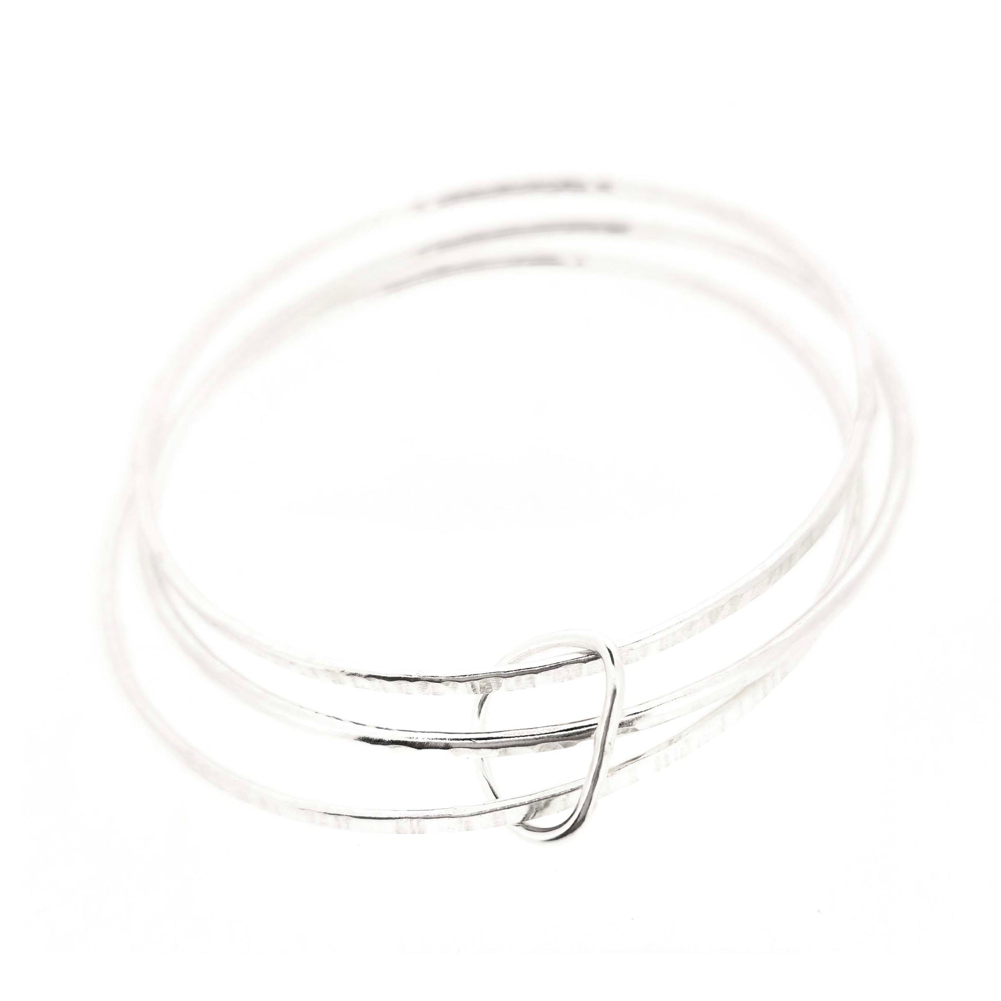 Triple textured silver bangle connected with soft edged open triangle charm.