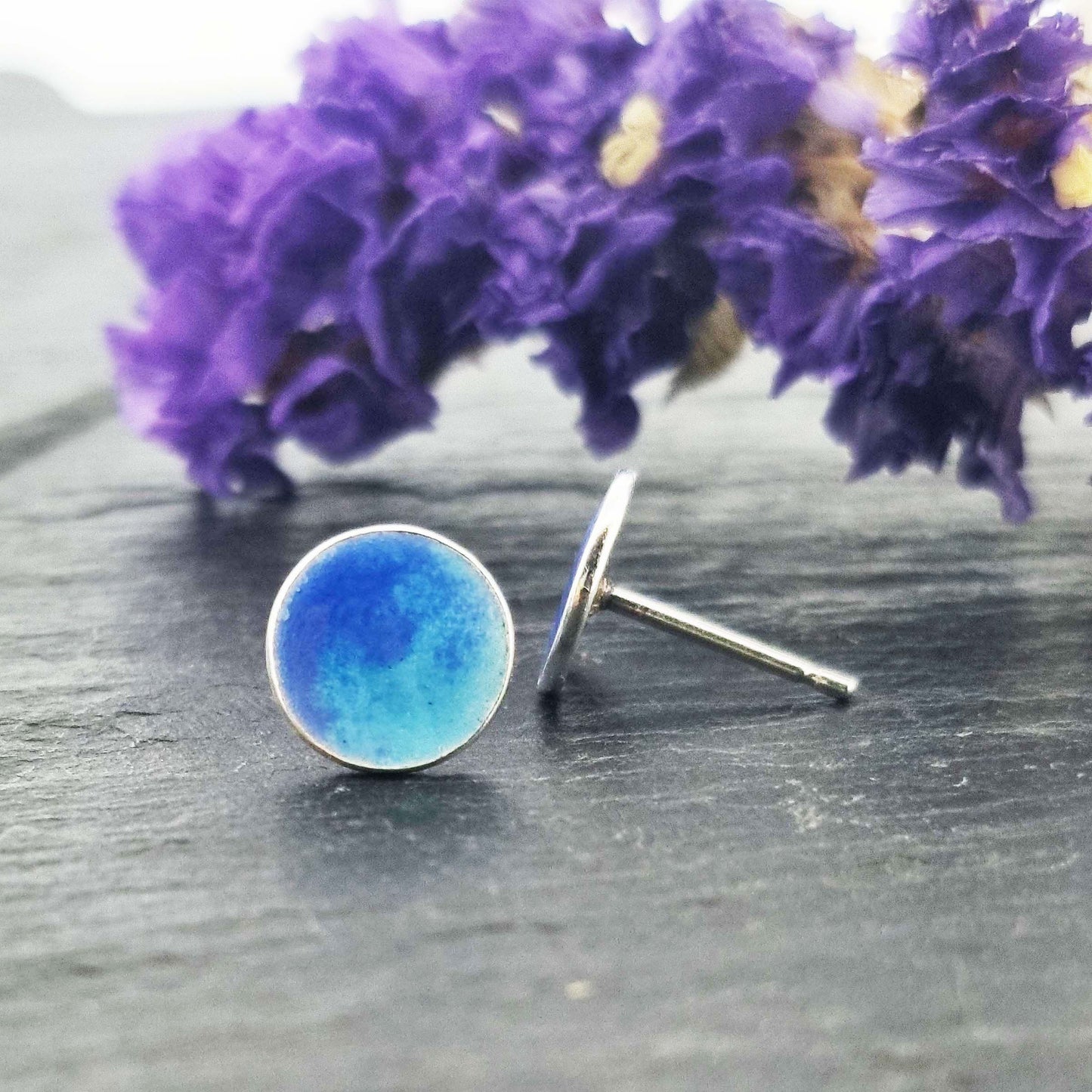 Round silver stud earrings with a mix of blue enamels.