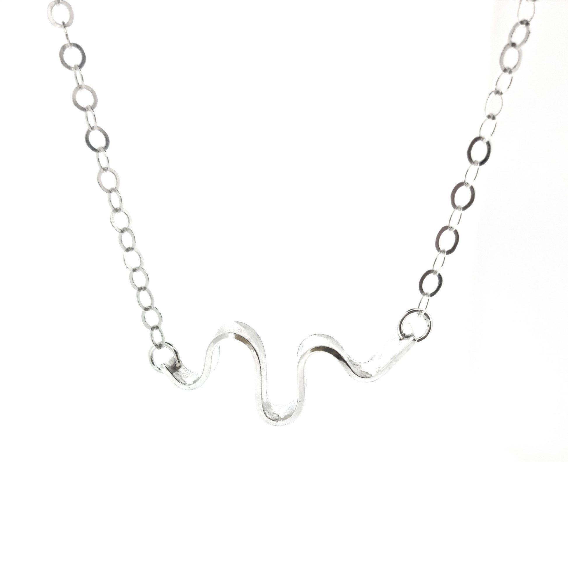 A silver necklace with an open chain and a wave of silver at the center.