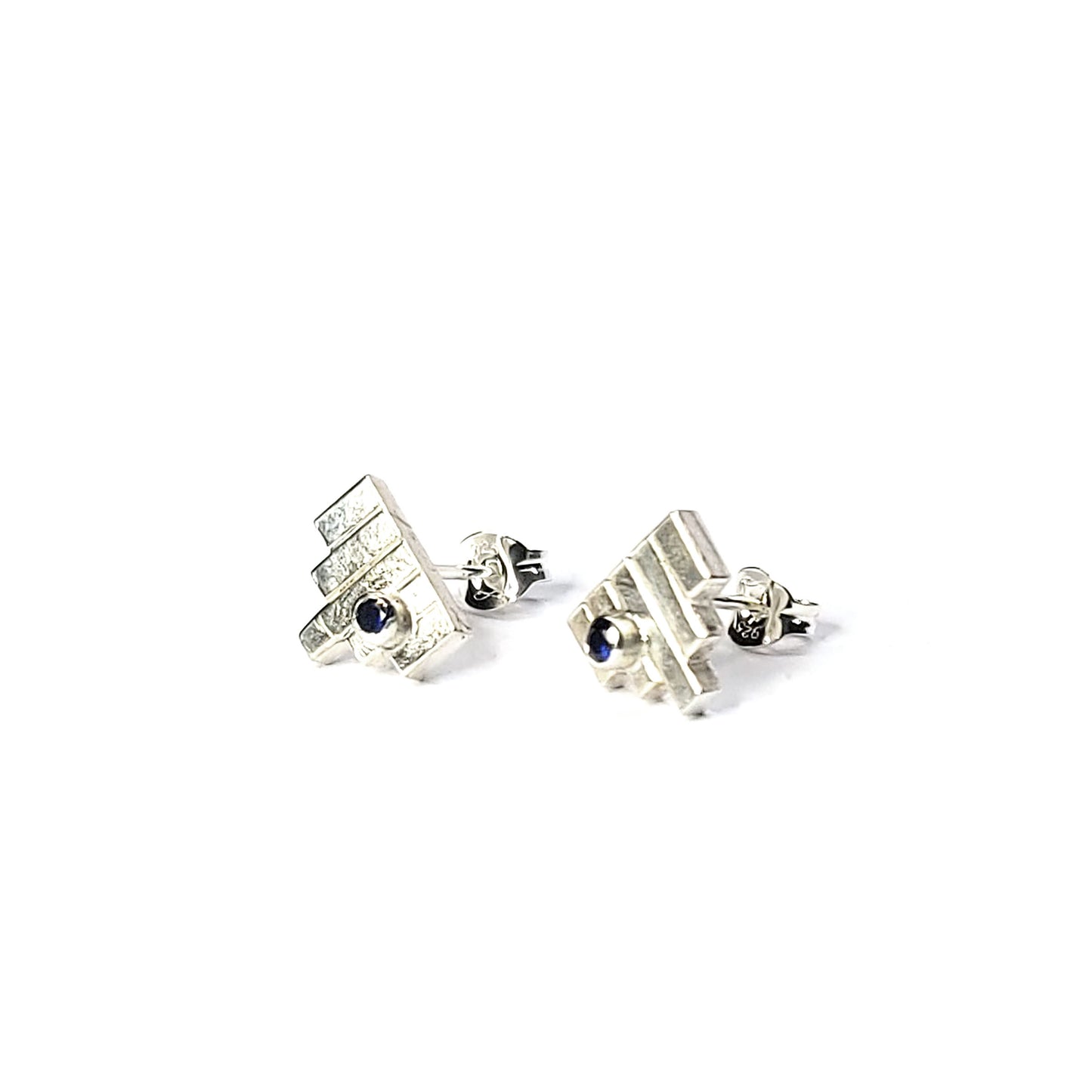 Silver Art Deco style stud earrings with 5 silver lines and off-centre dark blue sapphires.
