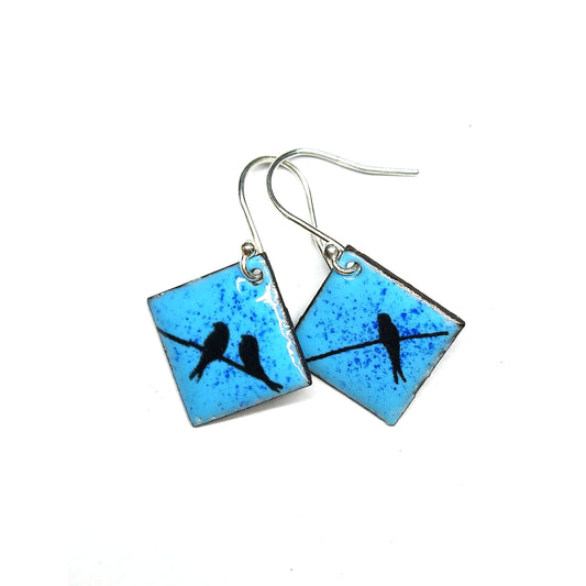 Square drop earrings featuring silhouettes of birds sitting on a wire against a blue enamel background.