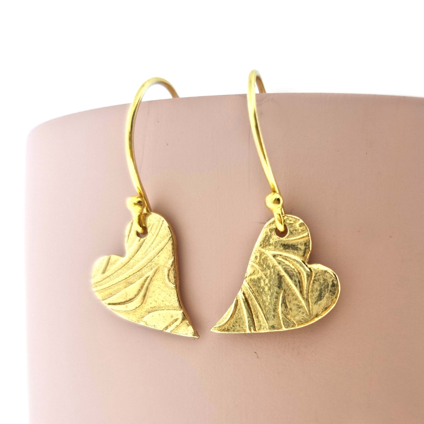Yellow gold vermeil drop earrings featuring an asymmetrical heart with a leaf vine pattern suspended from an ear wire.