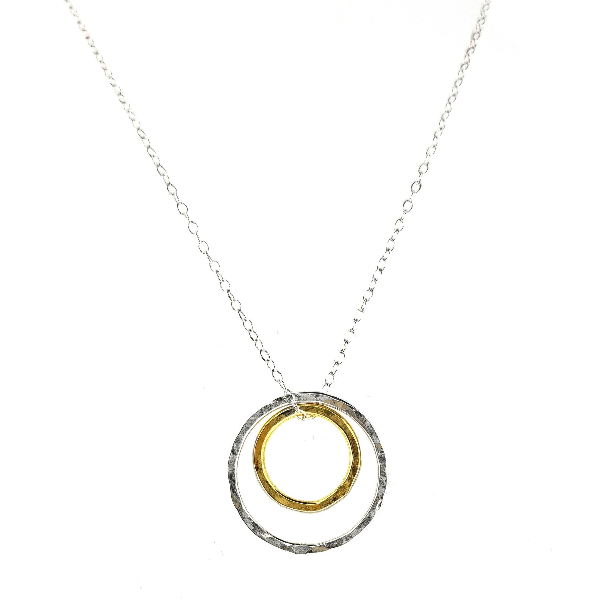 A double circle pendant with an inner yellow gold vermeil hammered circle and an outer silver hammered circle. Suspended on a silver chain.