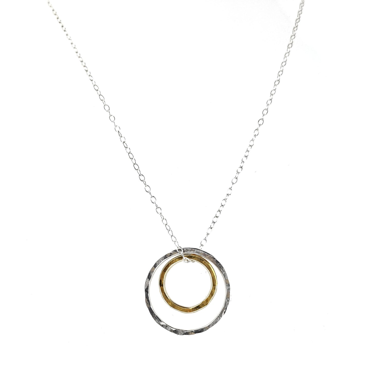 A double circle pendant with an inner yellow gold vermeil hammered circle and an outer silver hammered circle. Suspended on a silver chain.