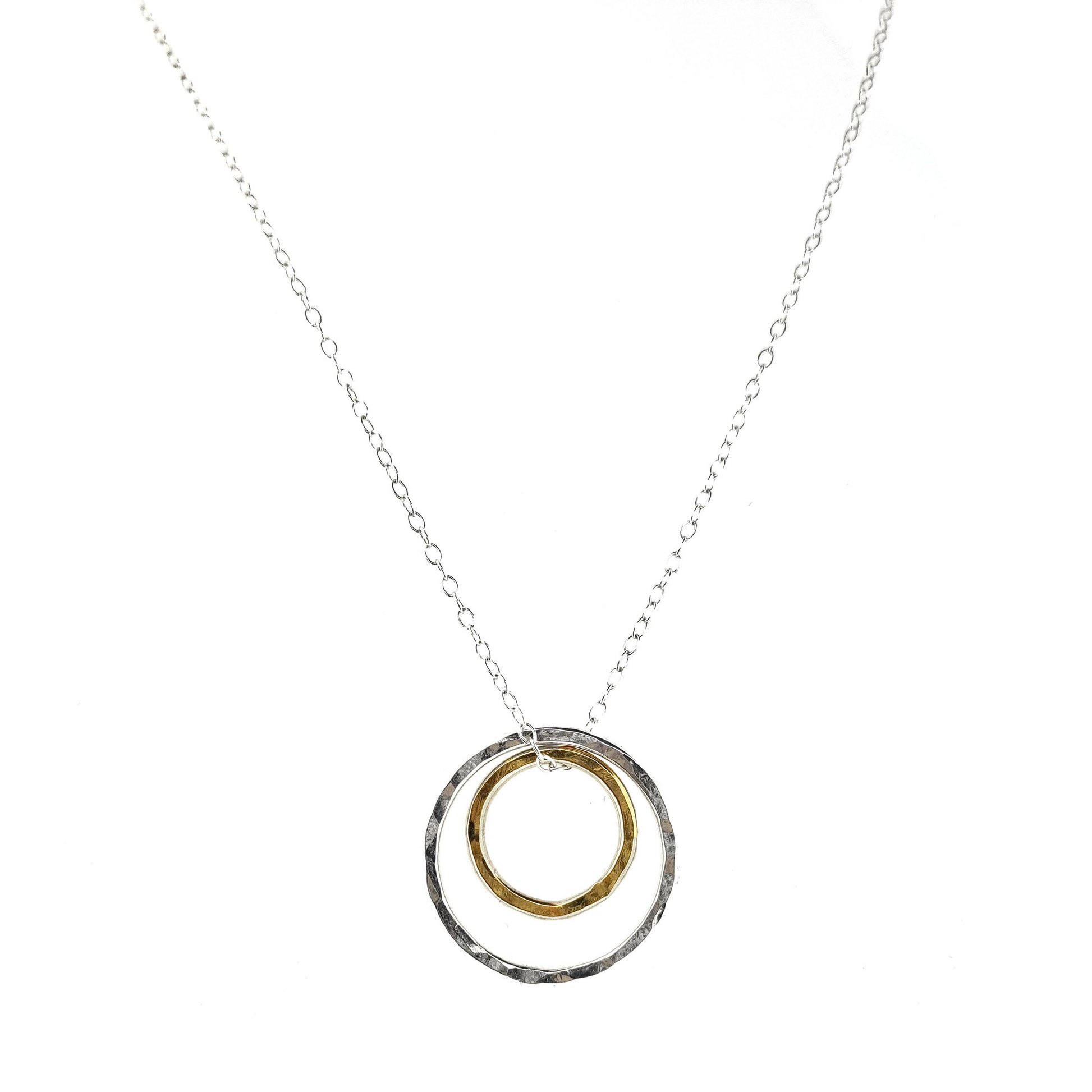 A double circle pendant with an inner yellow gold vermeil hammered circle and an outer silver hammered circle. Suspended on a silver chain.