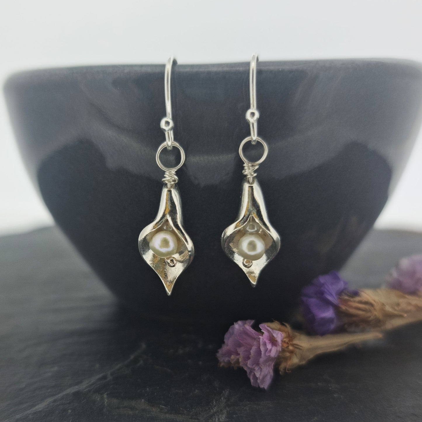 Silver calla lily drop earrings with pearls in the centre. - small on bowl with flowers