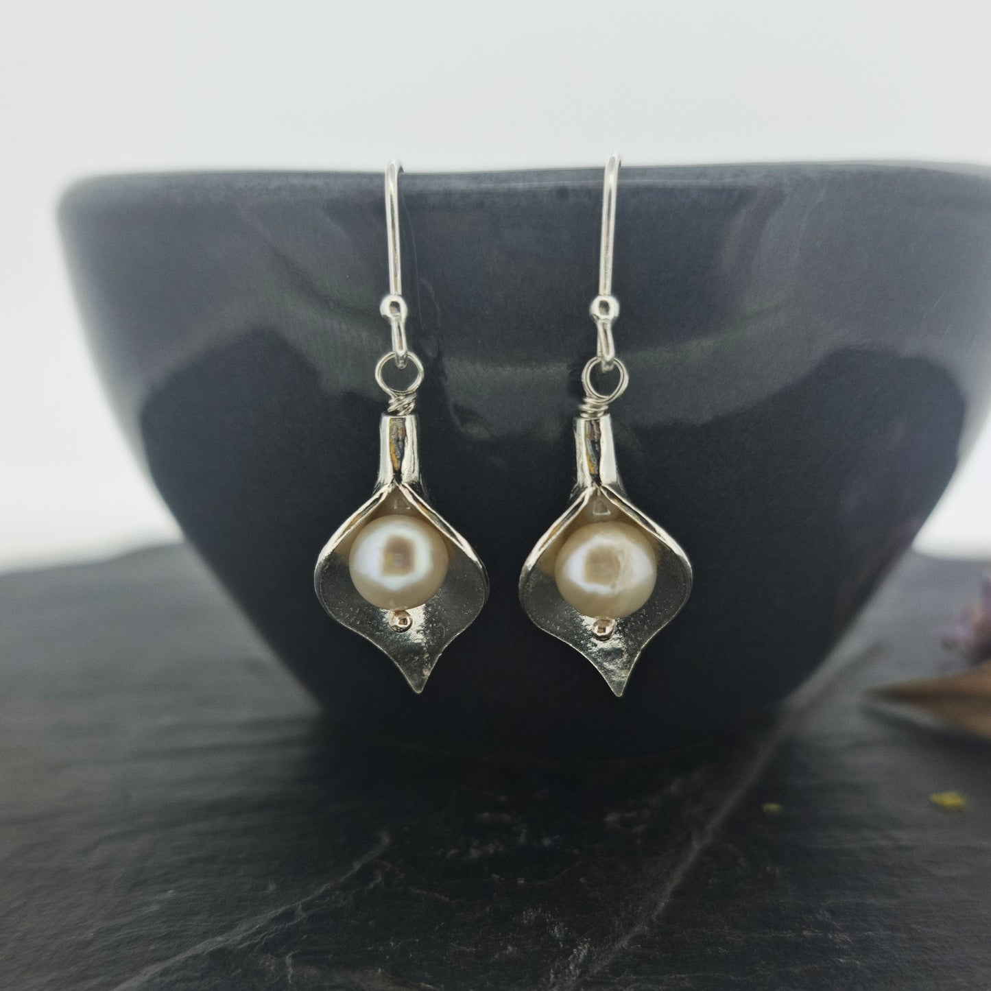 Silver calla lily drop earrings with pearls in the centre. - large - on bowl