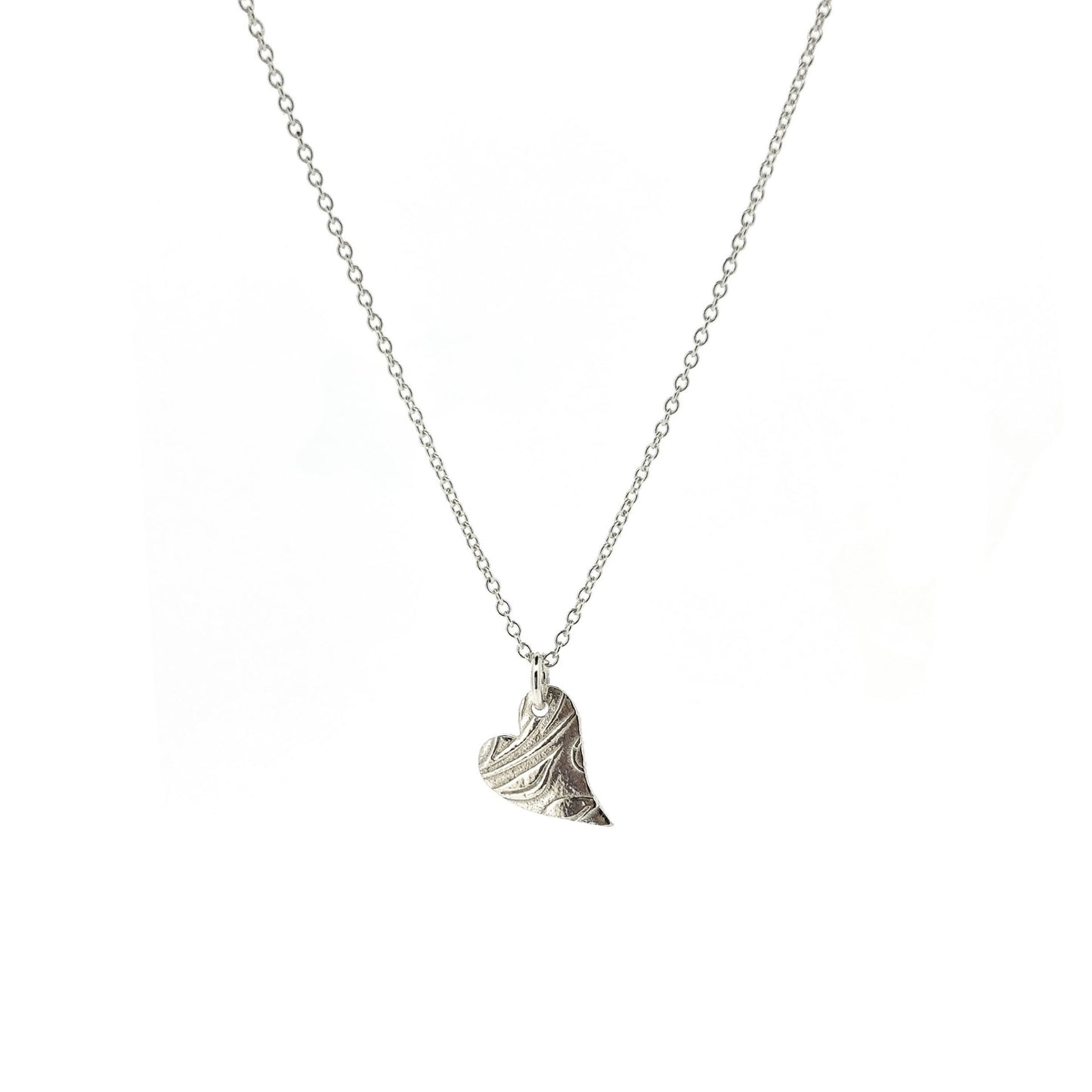 A silver asymmetrical heart pendant with a leaf and vine pattern suspended on a silver chain - small