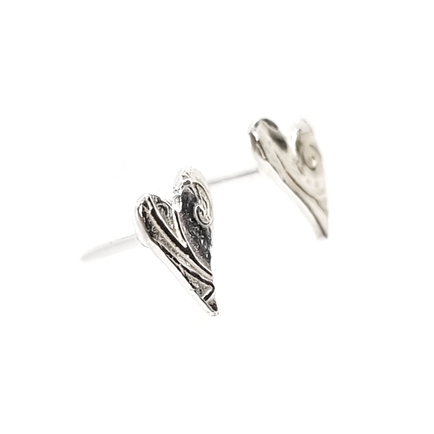 Silver asymmetrical heart stud earrings with a swirl pattern.