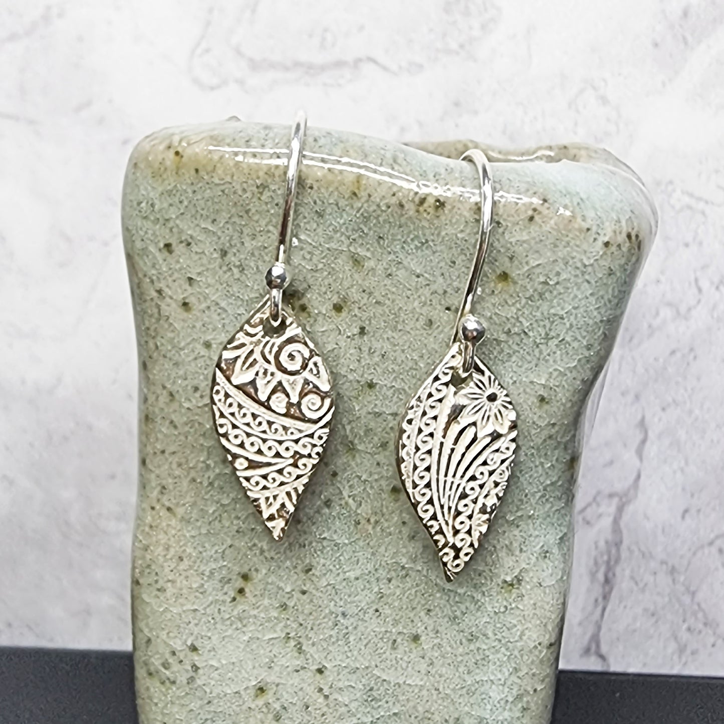 Silver leaf shaped drop earrings with pattern.