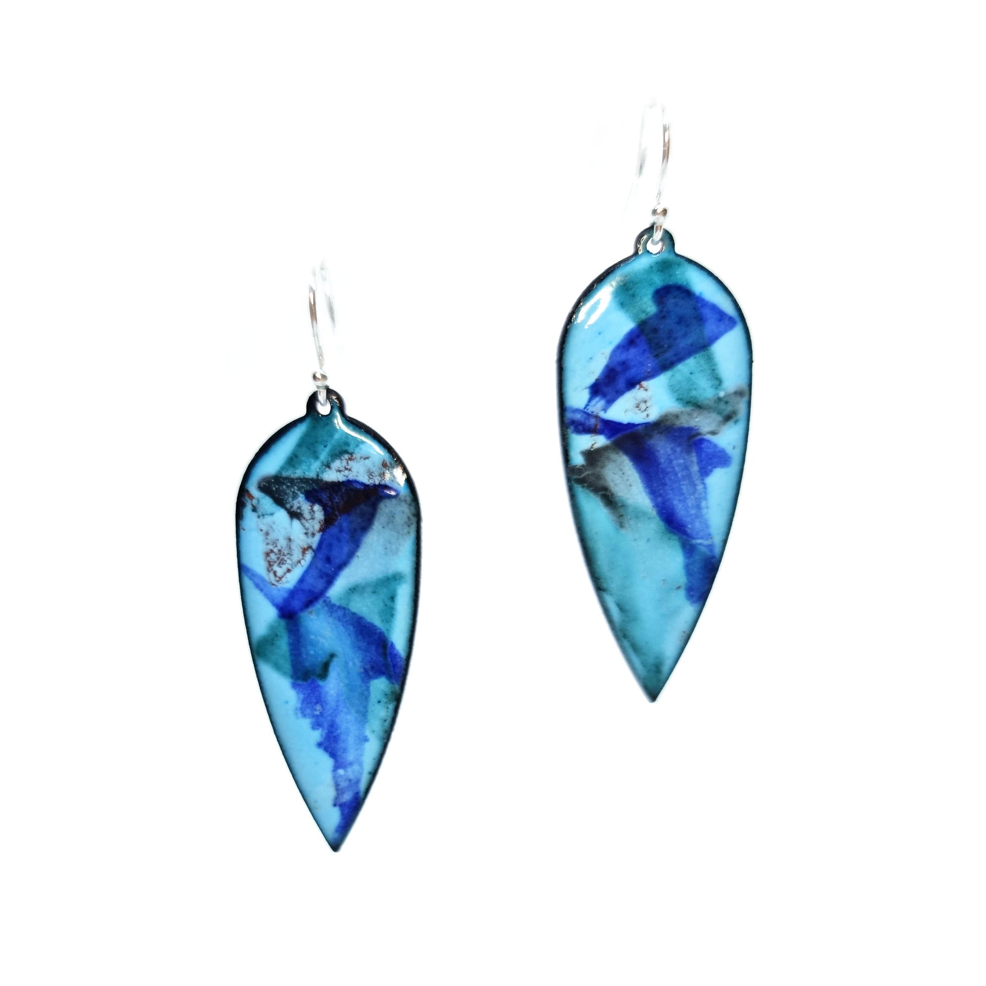 Large teardrop shaped enamel drop earrings with splashes of dark blue, red, green and grey on a light blue background