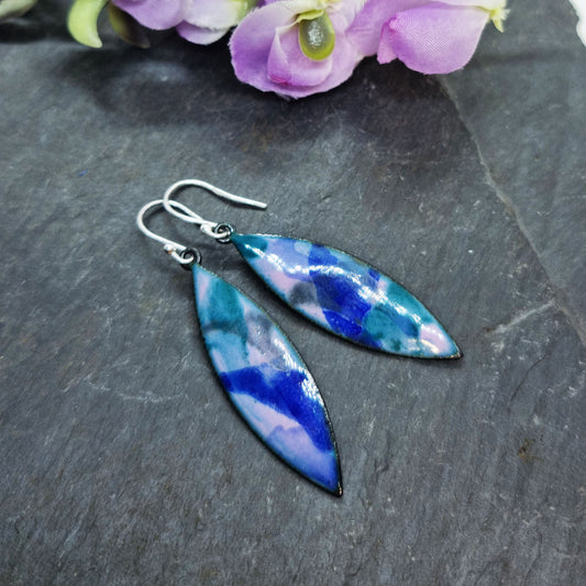 Boat-shaped enamel drop earrings with splashes of blue, green and grey on a light purple background - with flowers