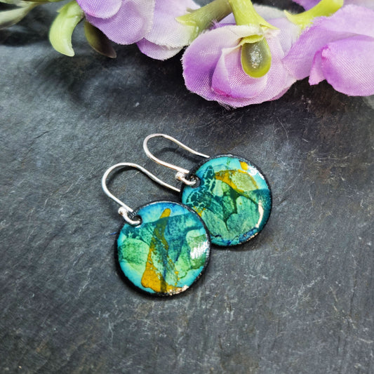 Round enamel drop earrings with splashes of blue, green and yellow on a light green background - with flowers