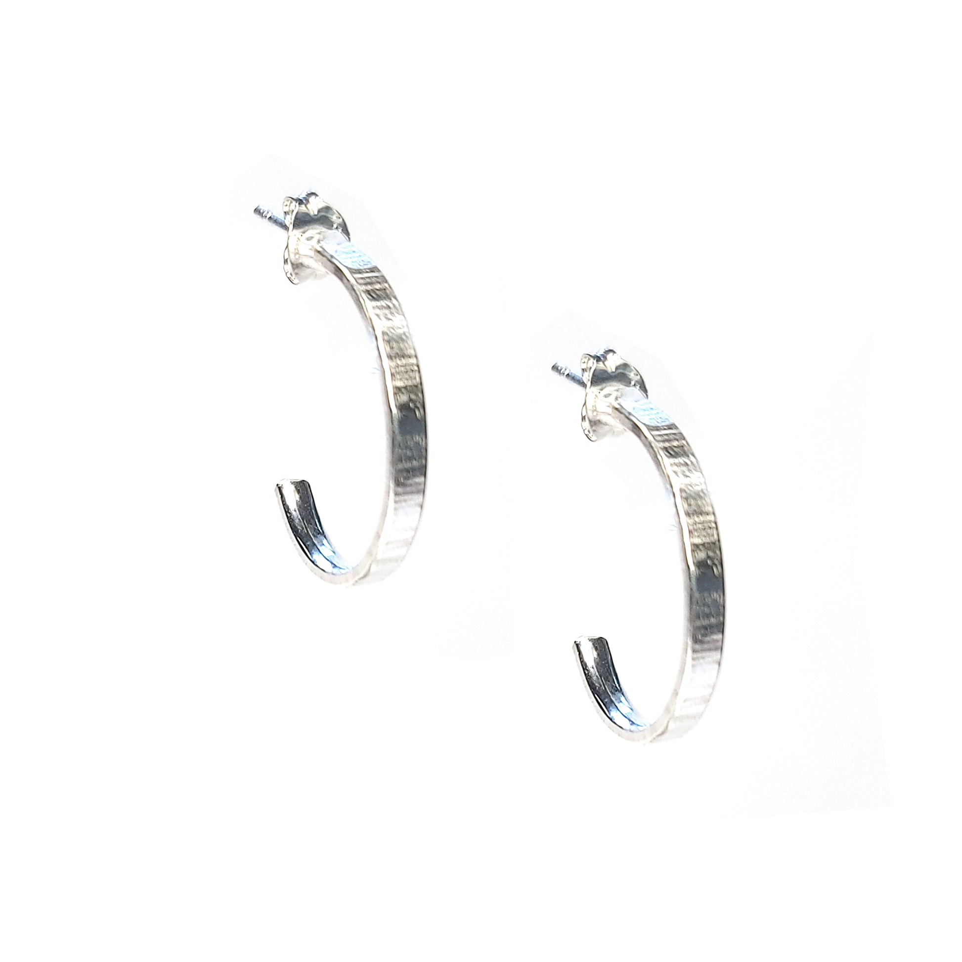 Silver flat hoop earrings with line texture.