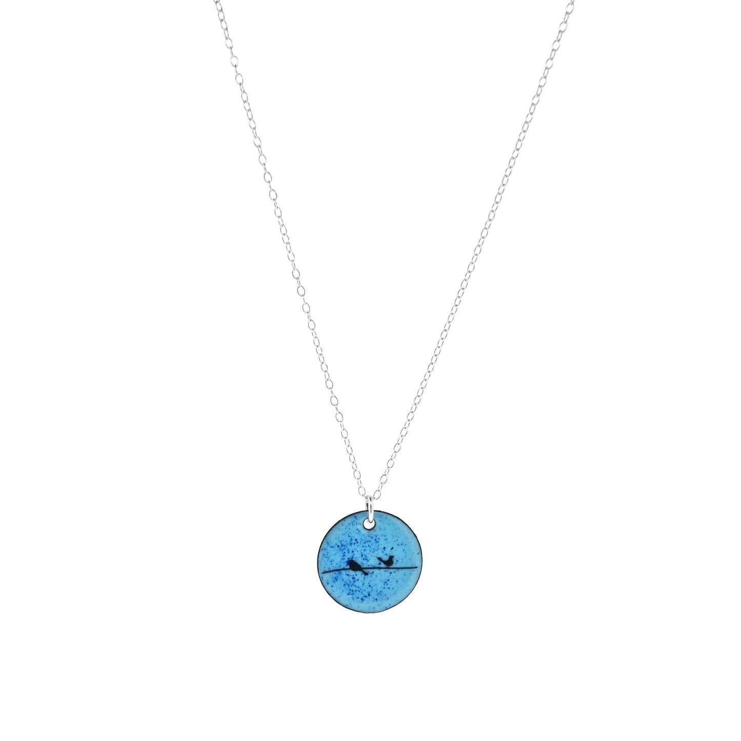 Round enamel pendant with bird silhouettes sat on a wire against a blue background. Suspended on a silver chain.