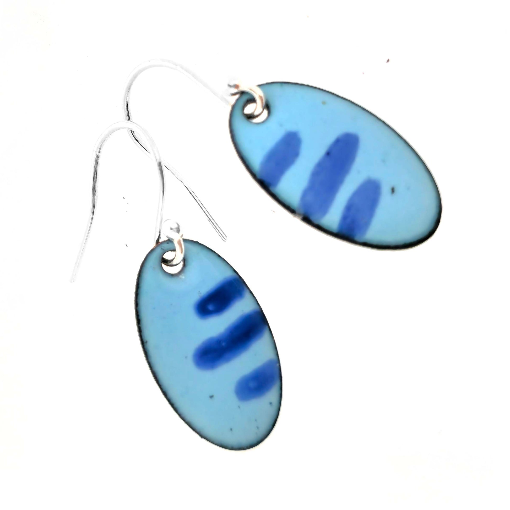 Pair of blue enamel oval earrings with a stripe pattern and silver ear hooks on a white background