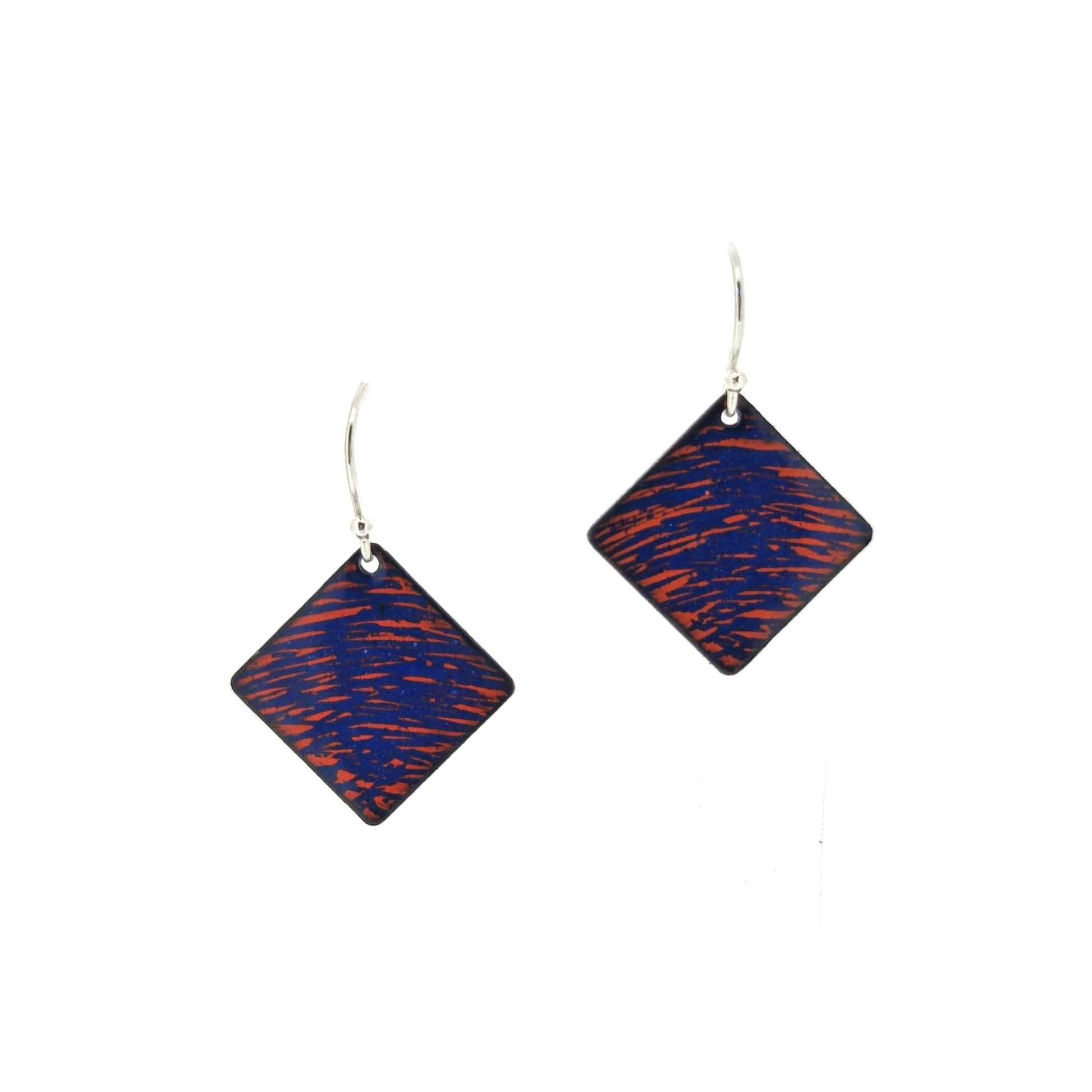 Square (diamond shaped) drop earrings with a rustic line pattern of dark blue and orange enamel. On silver ear hooks.