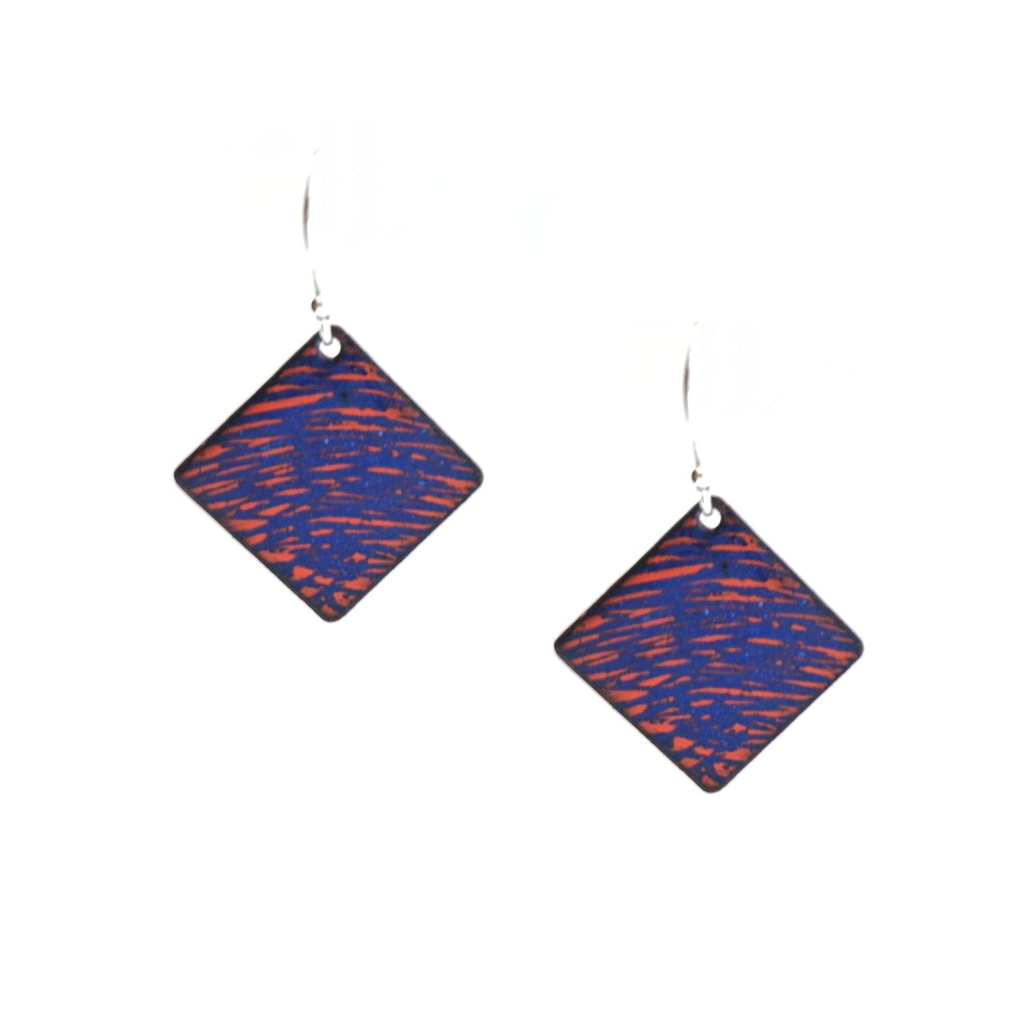 Square (diamond shaped) drop earrings with a rustic line pattern of dark blue and orange enamel. On silver ear hooks.