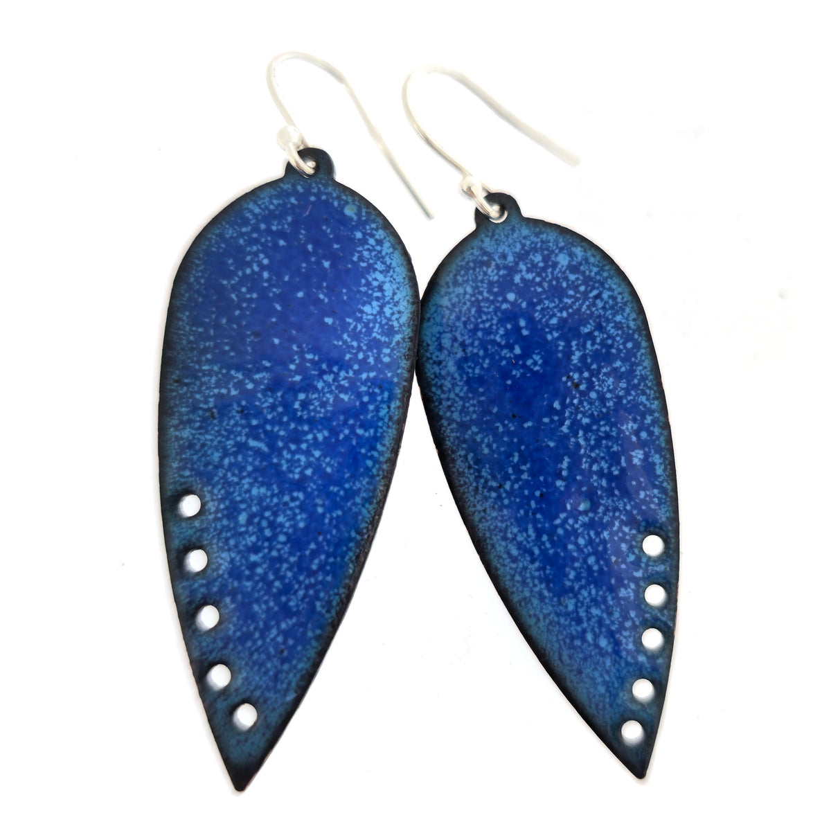 A pair of handmade teardrop-shaped blue enamel dangle earrings with silver fishhook wires and small circle cutouts along the lower edge, shown against a plain white background. Mijoux jewellery.