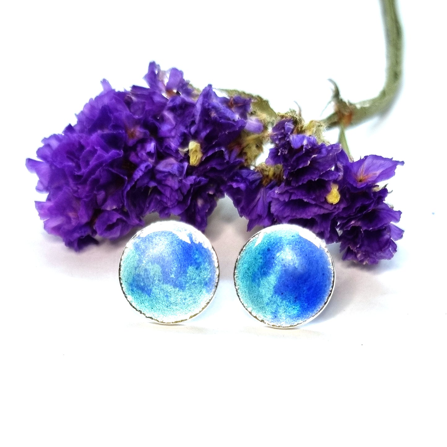 Round silver stud earrings with a mix of blue enamels. Pictured with flowers.