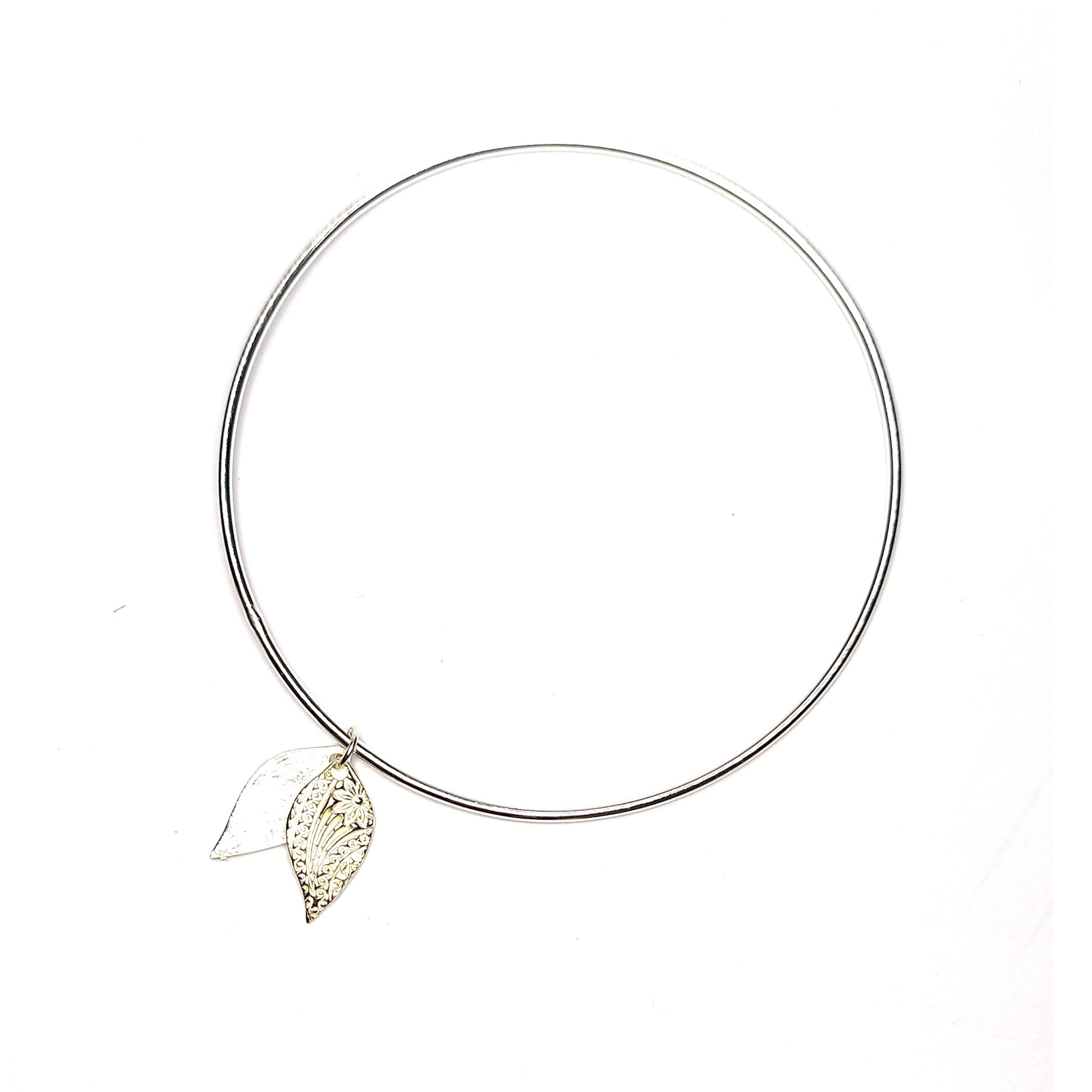 A round silver bangle with a double leaf-shaped patterned charm.