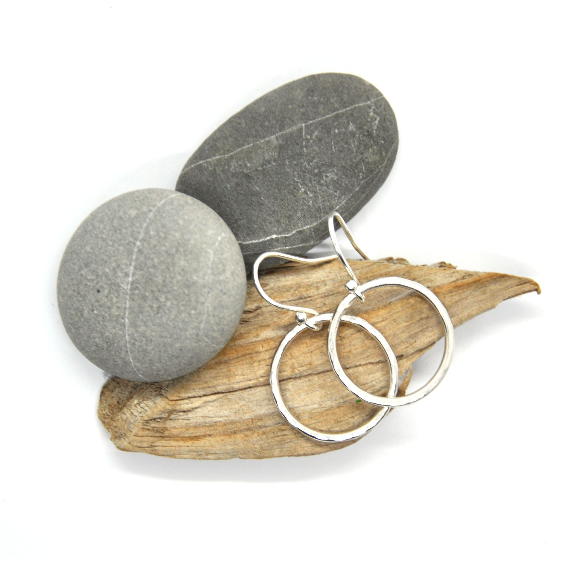 Sterling silver open circle drop earrings with hammered finish - large. On wood and pebbles.