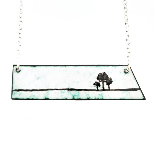 Handmade necklace with a silver chain and an enamel panel pendant showing a group of 3 tree silhouettes against a white and green background. Handmade. Mijoux Jewellery.