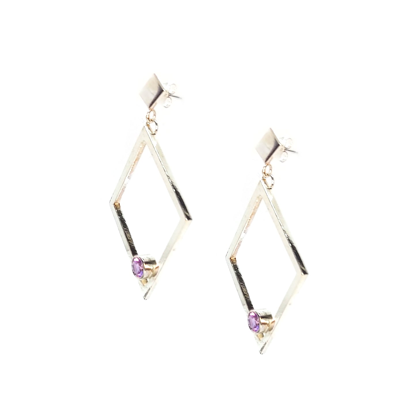 A pair of silver statement earrings featuring a top diamond shaped stud with a large open diamond shape drop beneath. Inside at the bottom of the large drop diamond is a round purple amethyst.