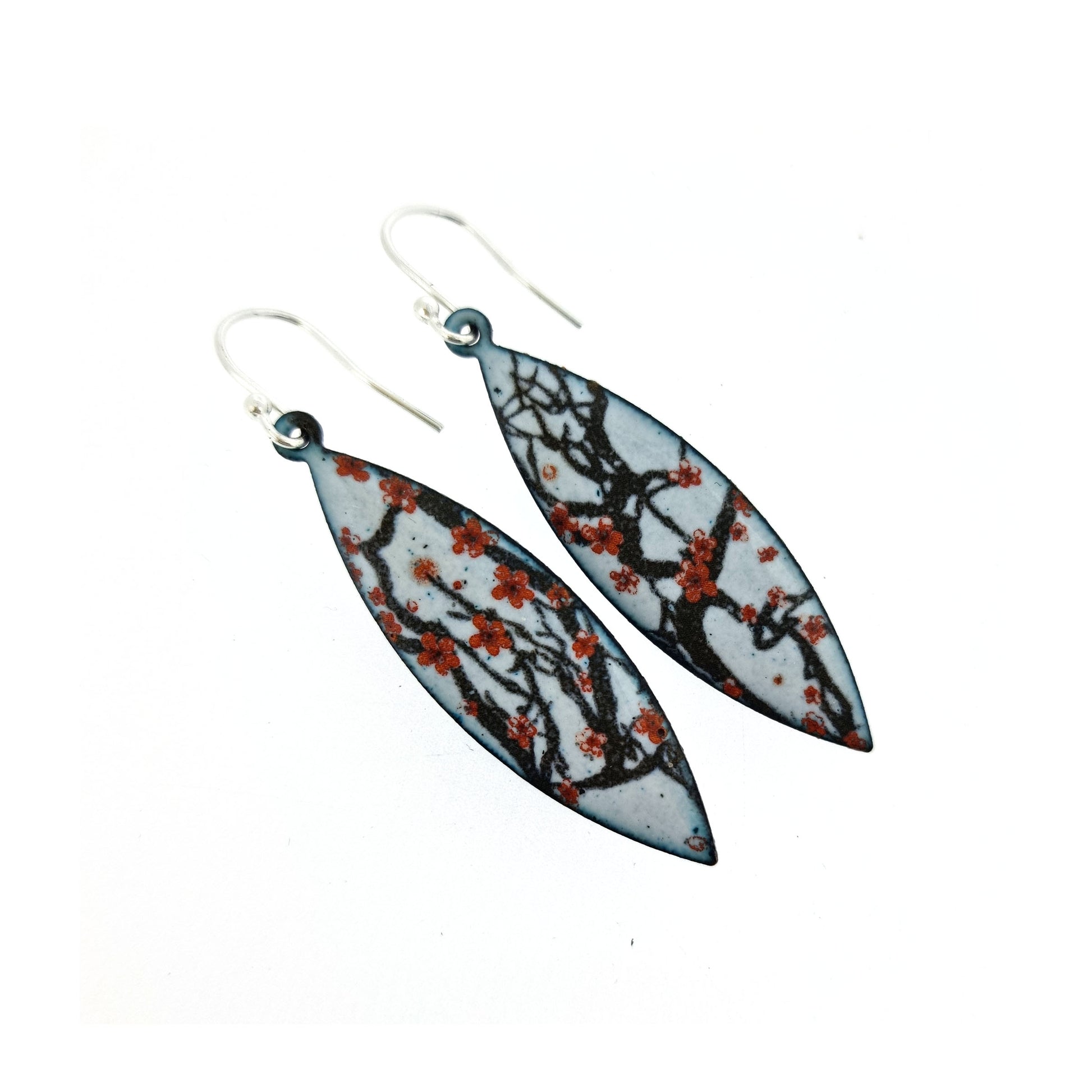 Boat-shaped enamel drop earrings with branches of red cherry blossom on a grey background.