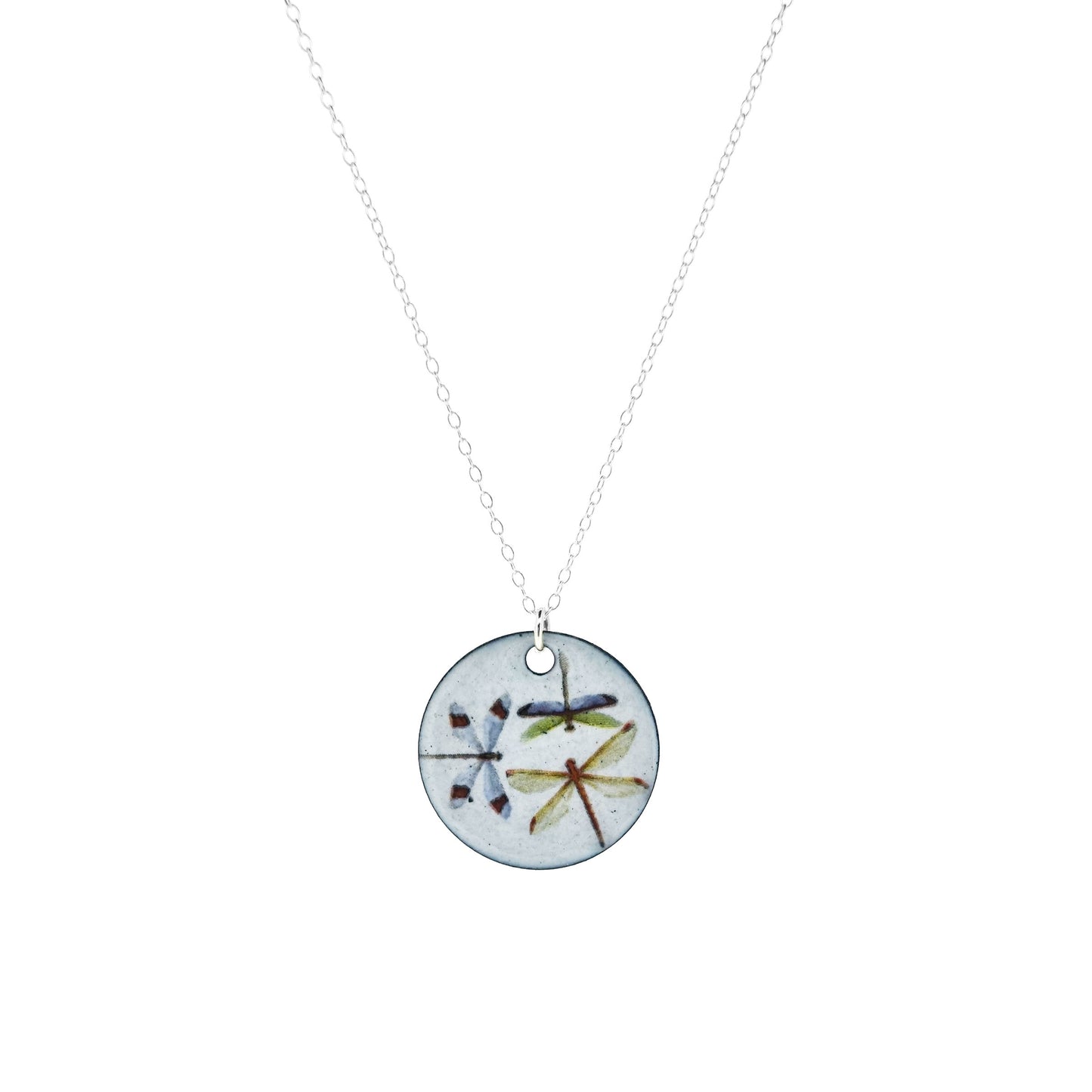 A round enamel pendant hangs from a silver chain. The pendant has a light grey background and 3 dragonflies on it.