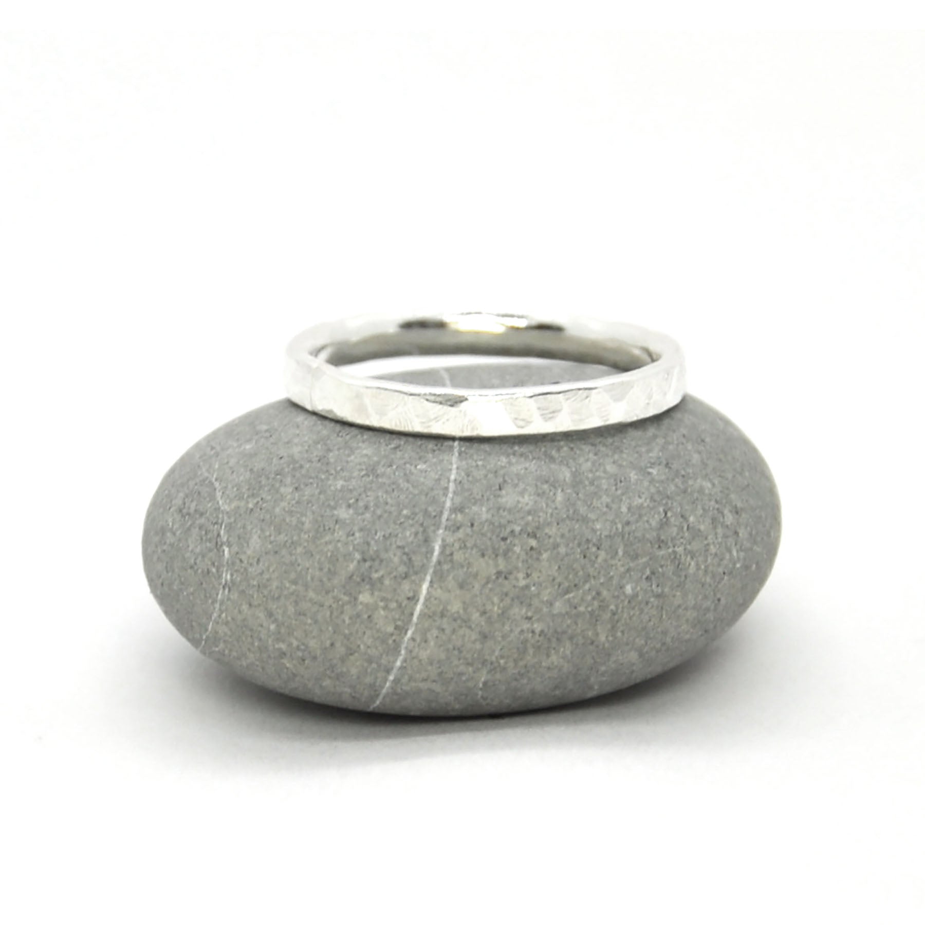 Silver hammered band ring. Pictured on a pebble.