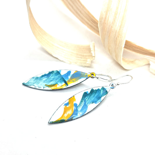 Navette shaped enamel drop earrings with green, blue and yellow splashes on a white background - with wood shavings