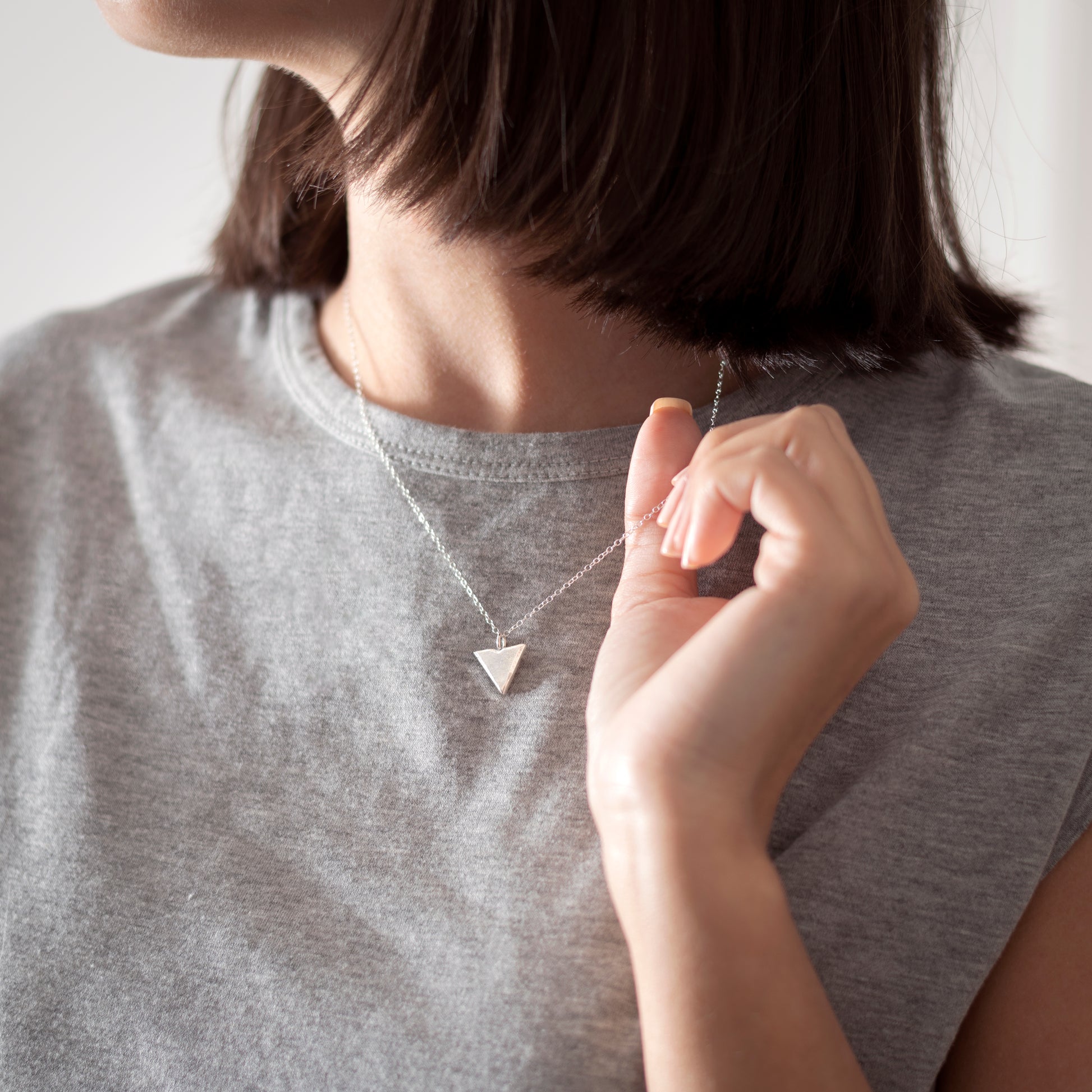 Silver triangle pendant on silver chain on model