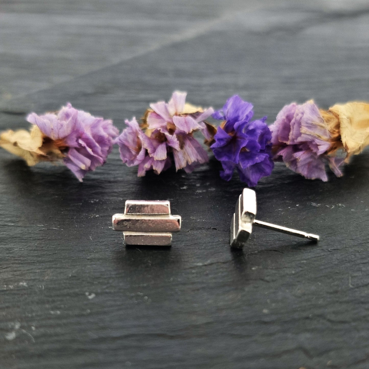 Silver Art Deco style stud earrings featuring 3 lines of silver. Pictured with flowers.