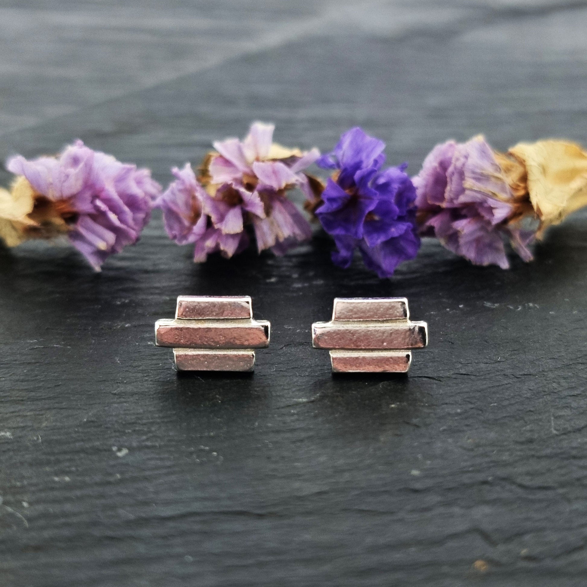 Silver Art Deco style stud earrings featuring 3 lines of silver. Pictured with flowers.