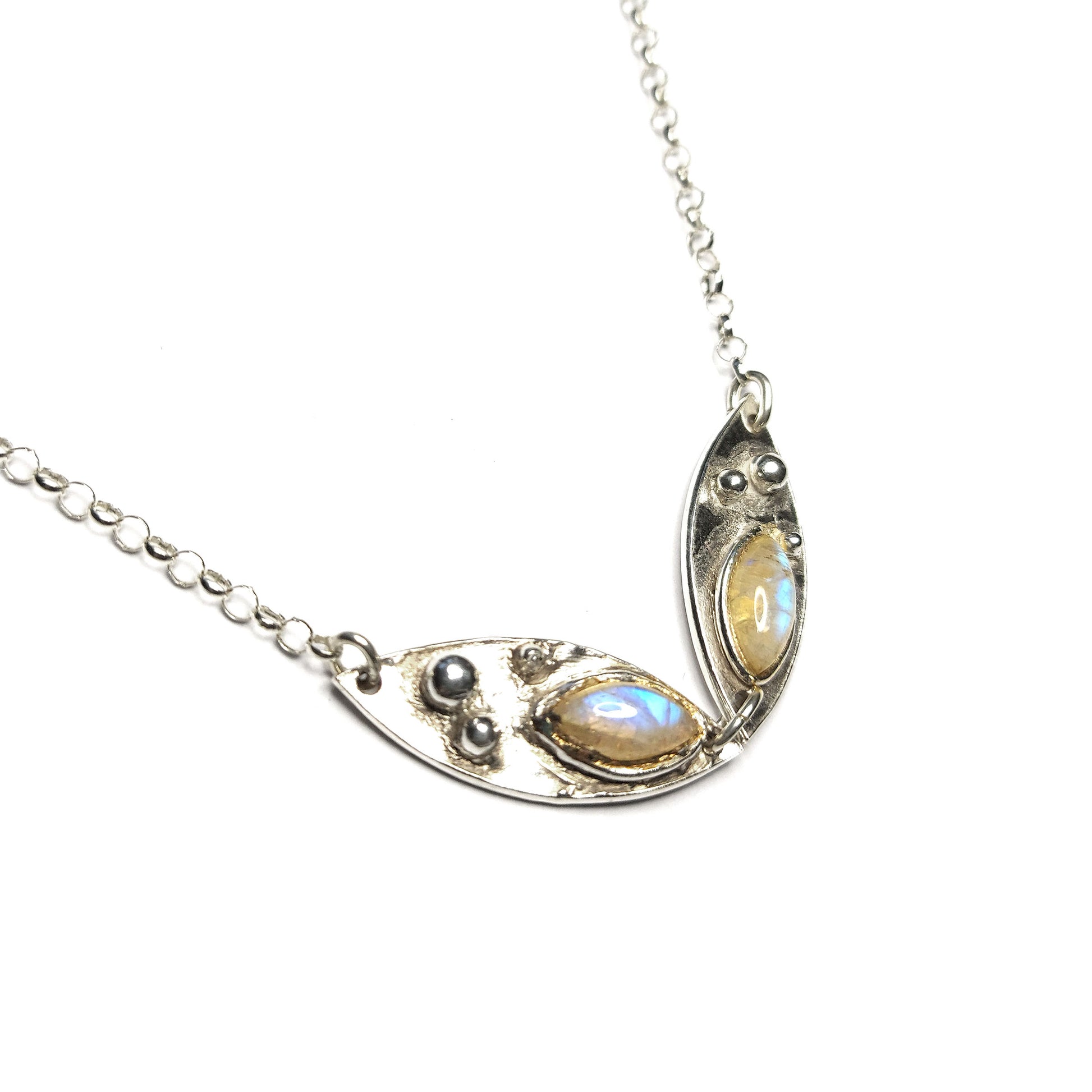 A silver chain necklace with two boat shaped bits of silver each set with a marquise moonstone and decorated with silver balls.