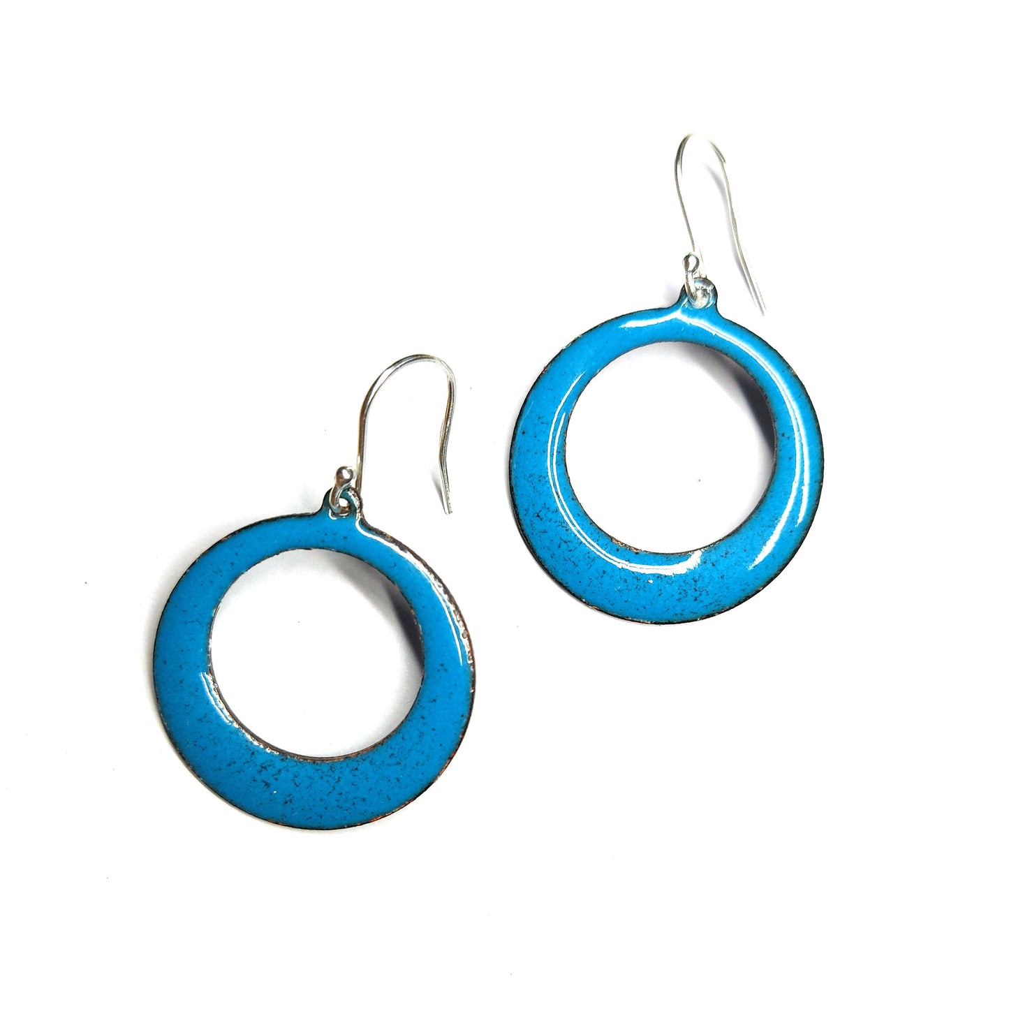 Enamel drop earrings featuring an open circle with teal enamel and a dusting of red enamel. On silver ear hooks.